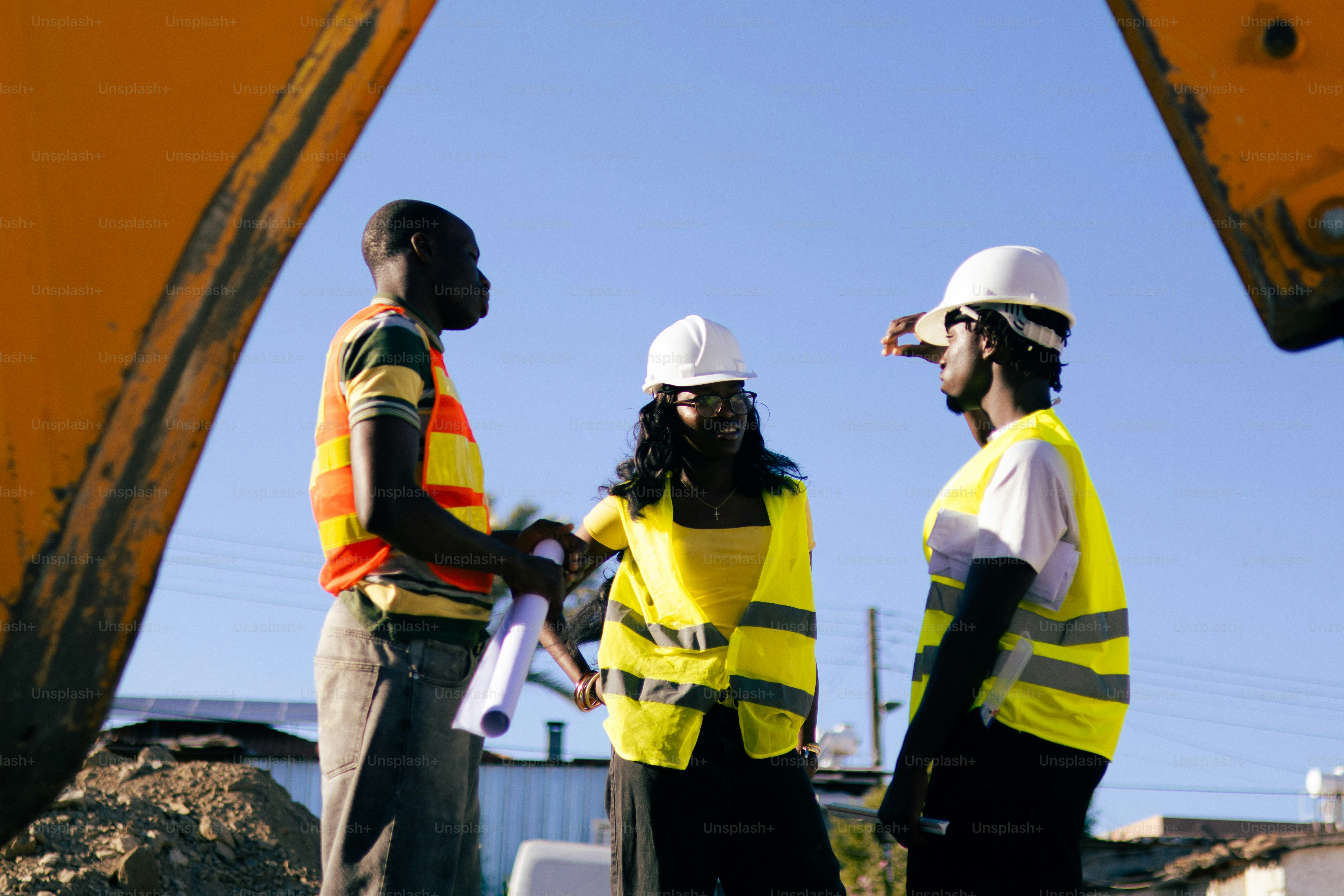 Two construction workers oversee a site with gravel and equipment ...