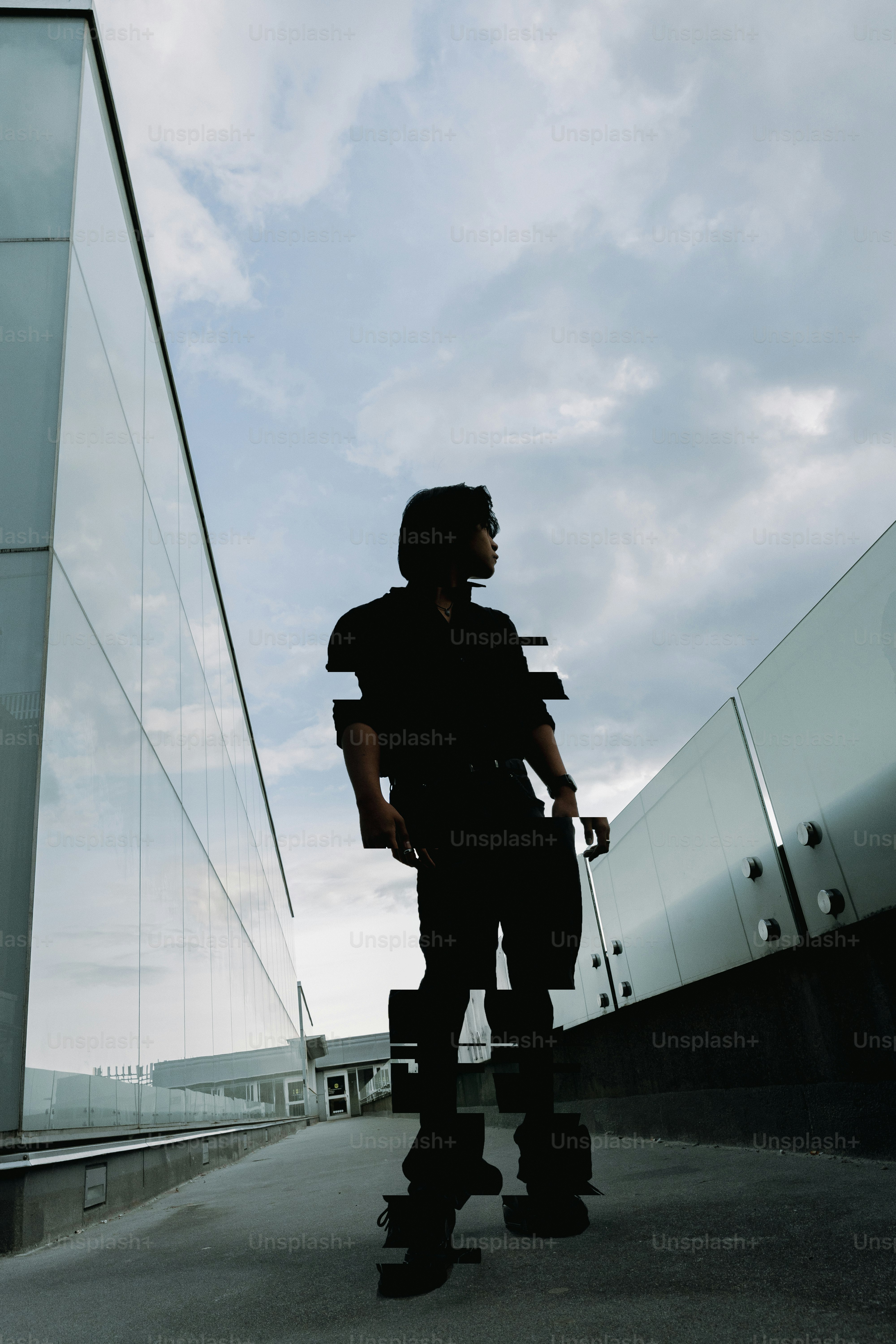 Orang bersiluet dengan efek glitch di atap bangunan modern.