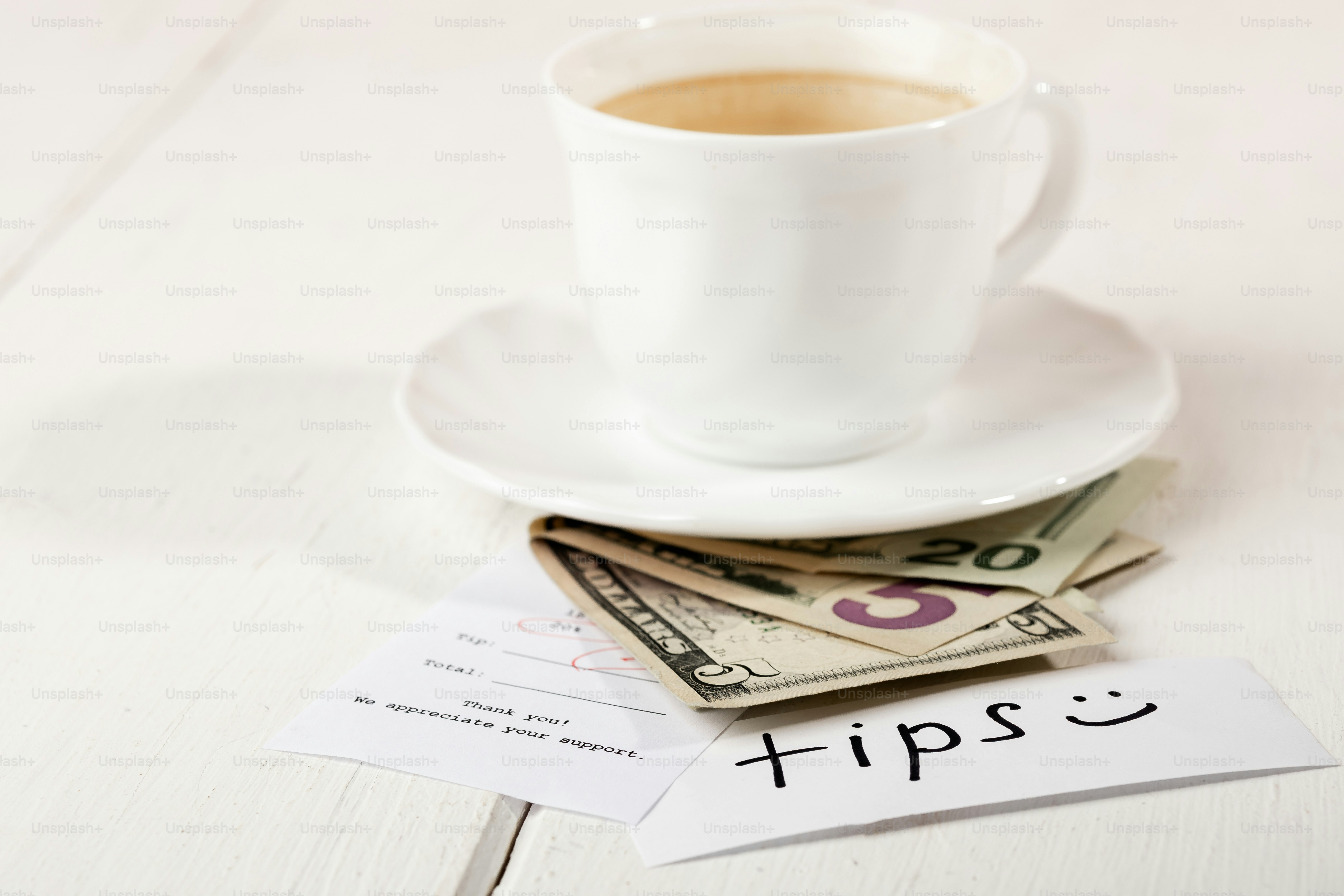 Cangkir kopi, uang, dan catatan "tip".