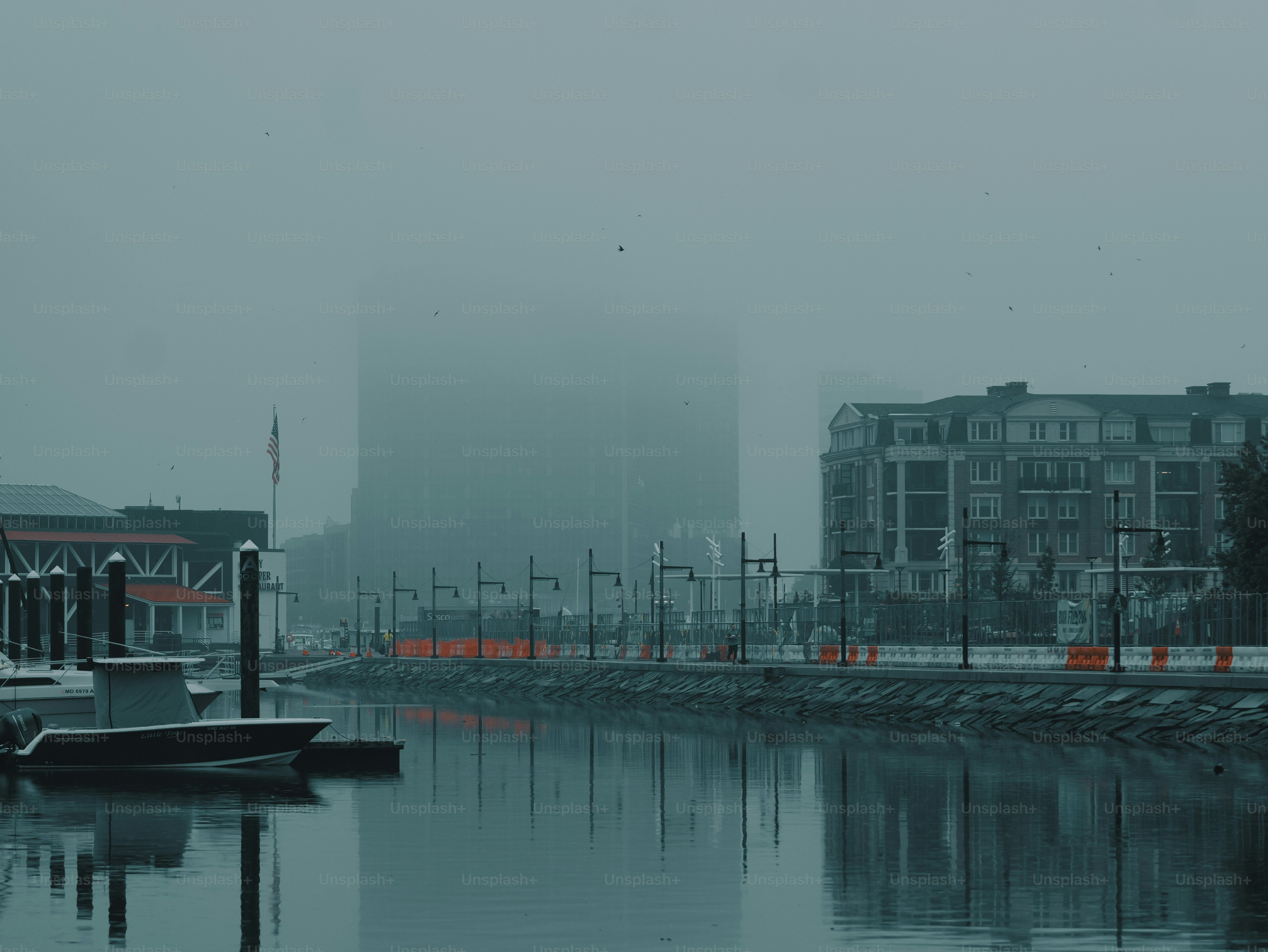 Foggy urban canal with buildings and a small boat.