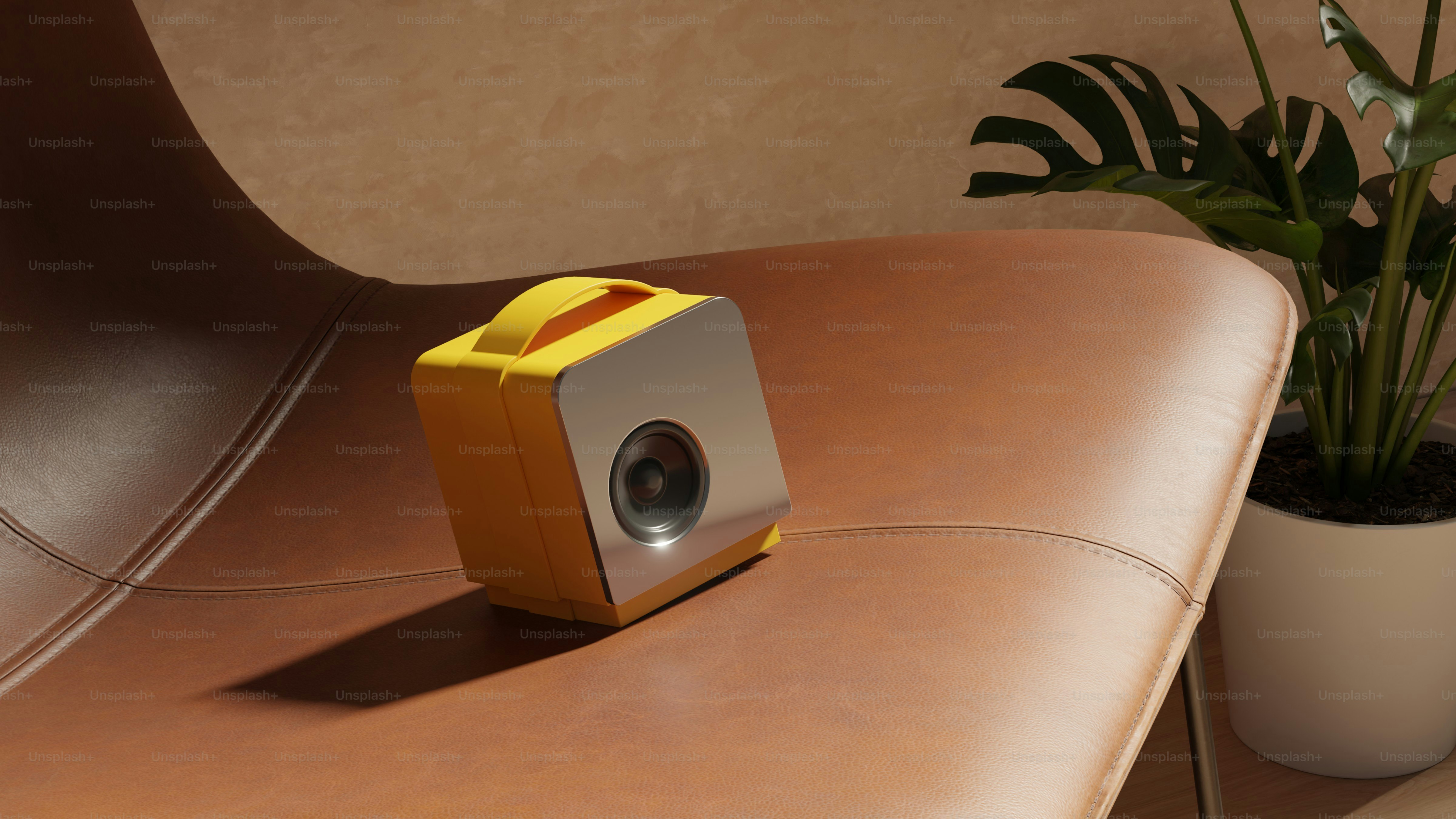 Proyector portátil amarillo y plateado sobre una silla de cuero marrón.