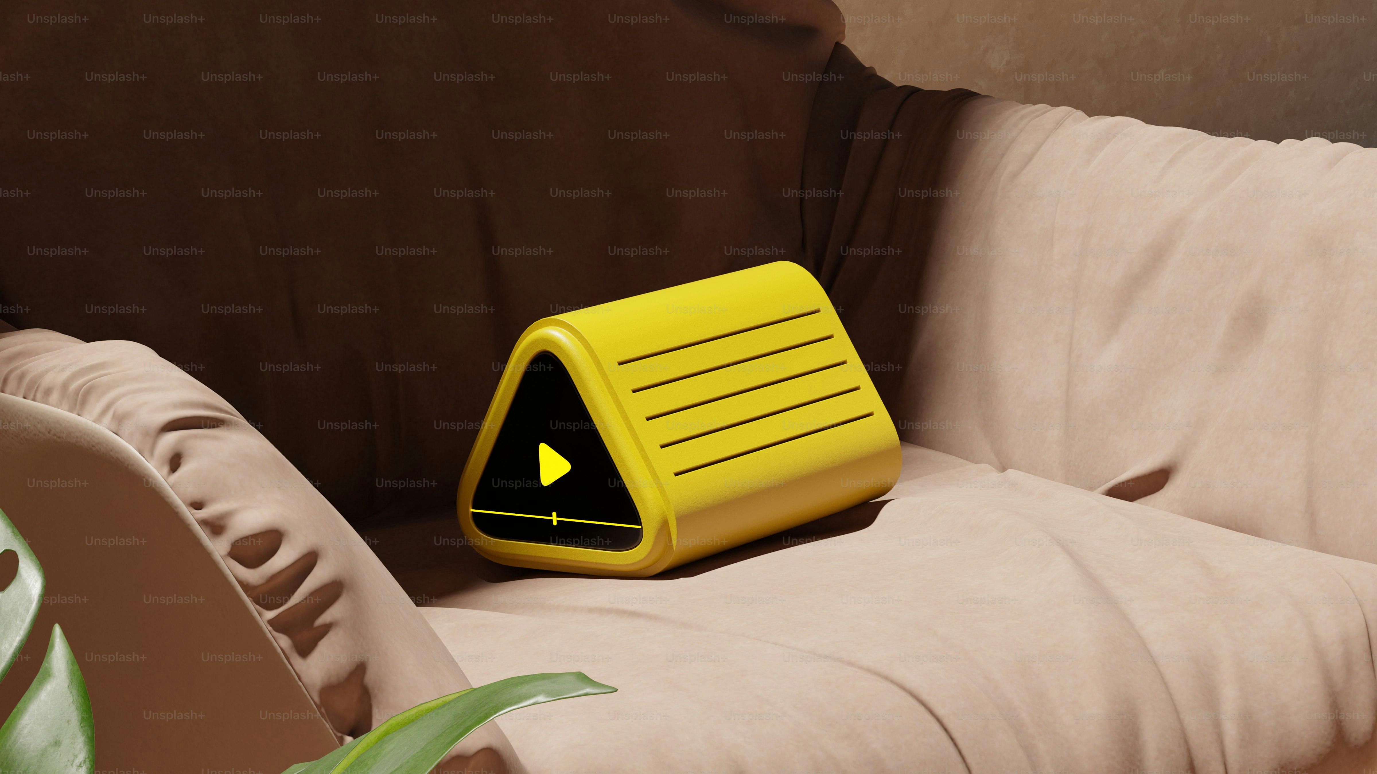 Dispositivo triangular amarillo sobre un sofá marrón.