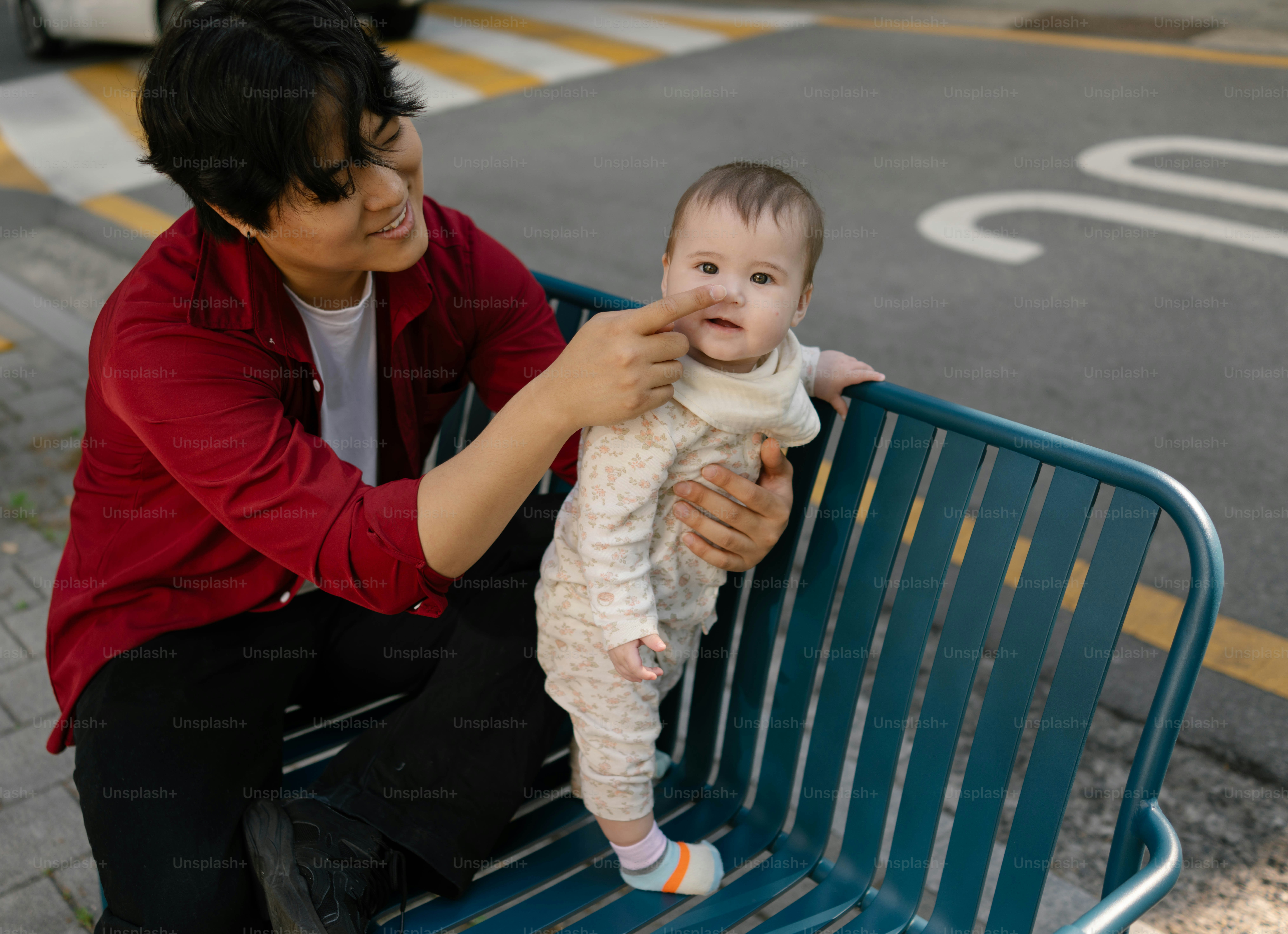 Seseorang dengan lembut menyentuh wajah bayi di bangku.