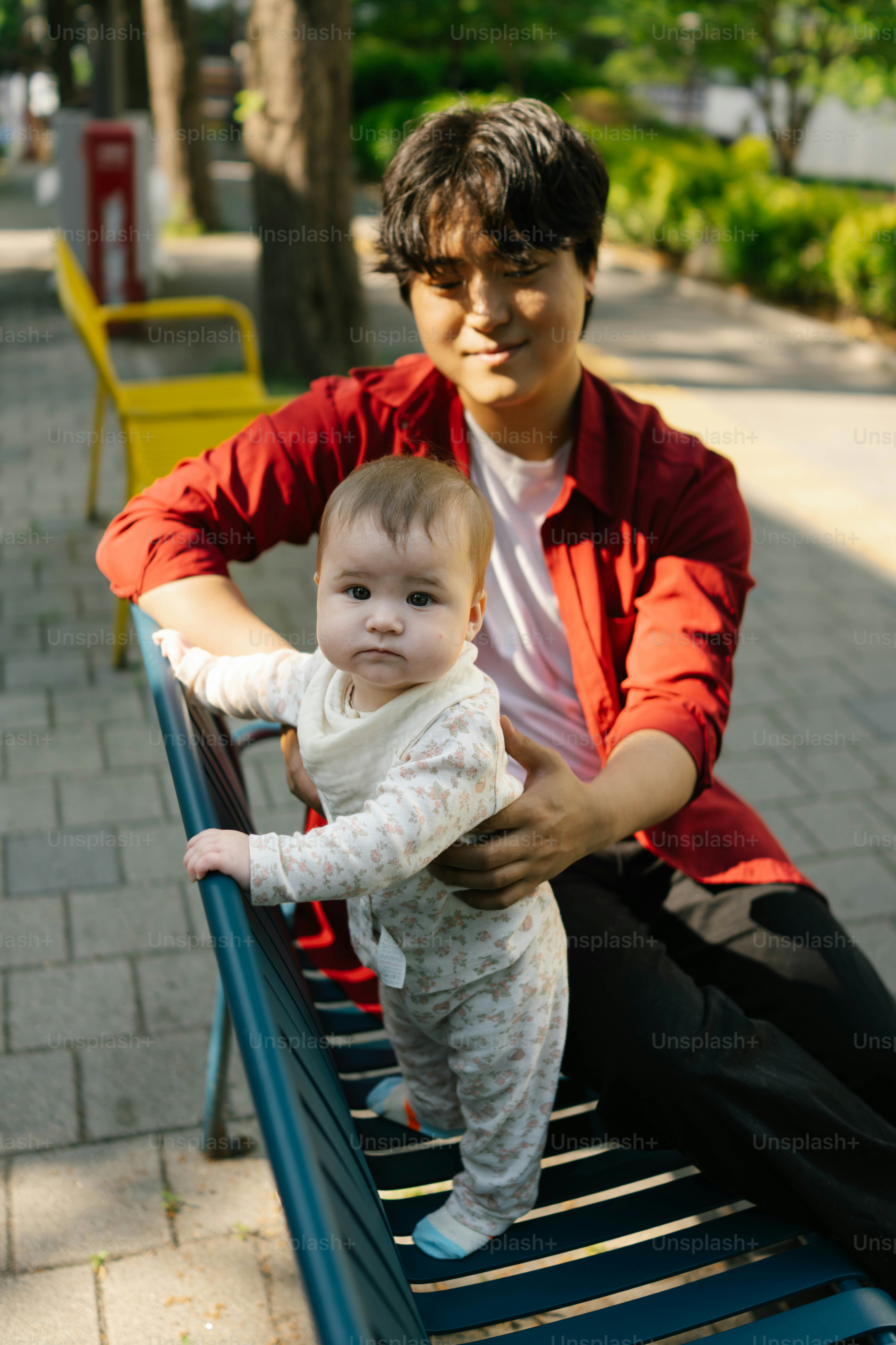Pria dan bayi berdiri di bangku taman biru.