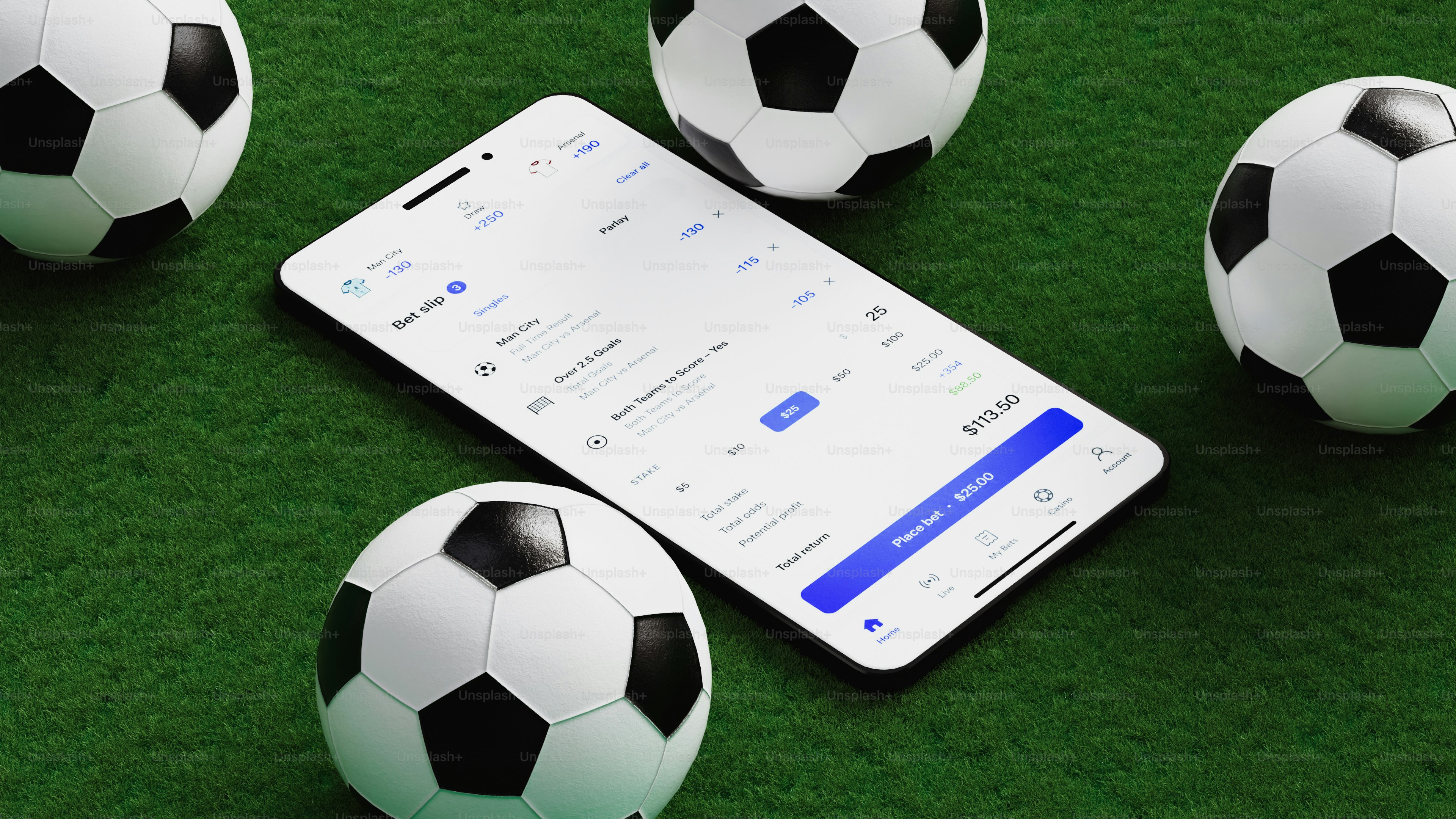 Smartphone and soccer balls on a green surface