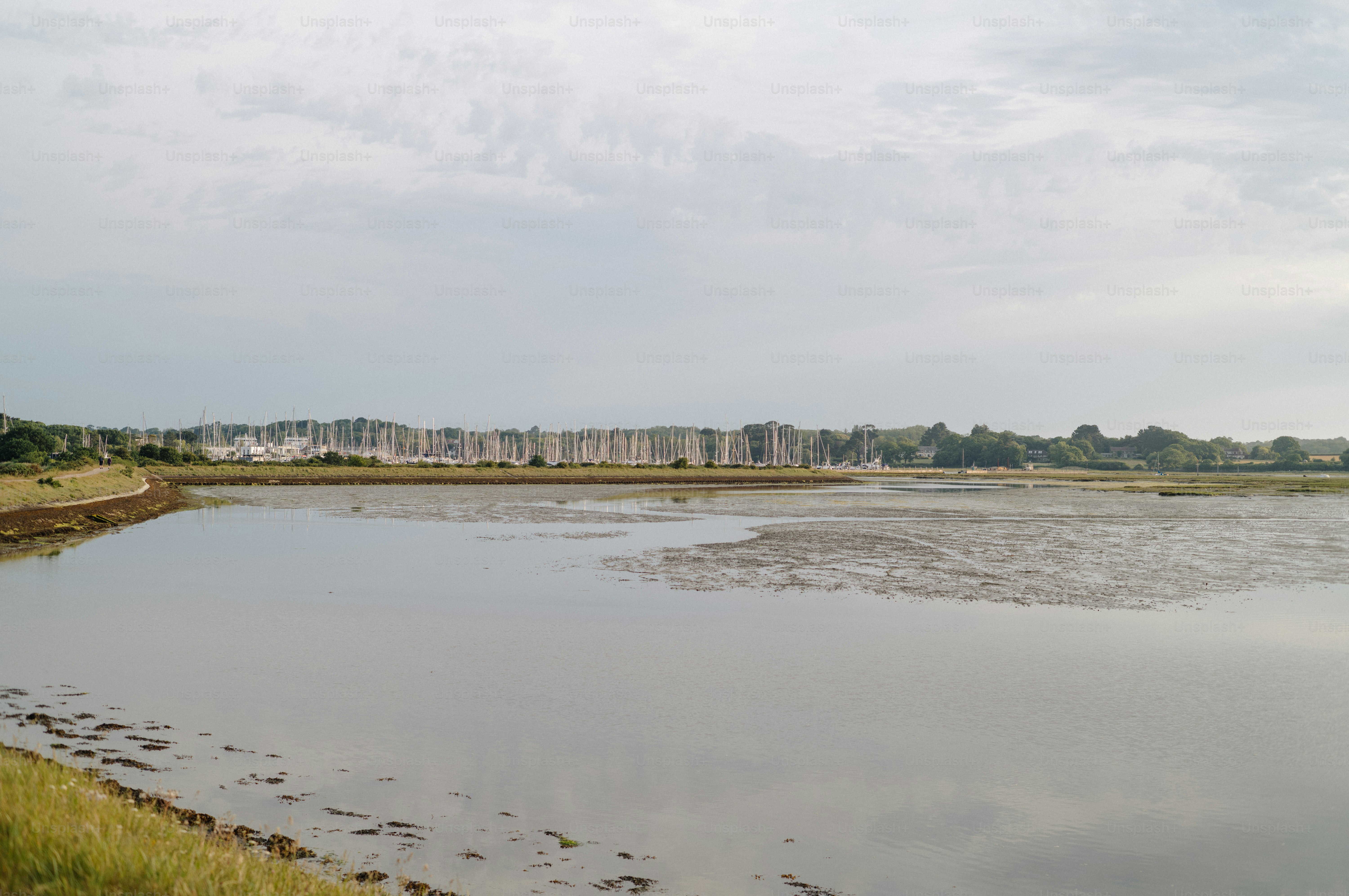 Still water reflects cloudy sky with distant buildings.