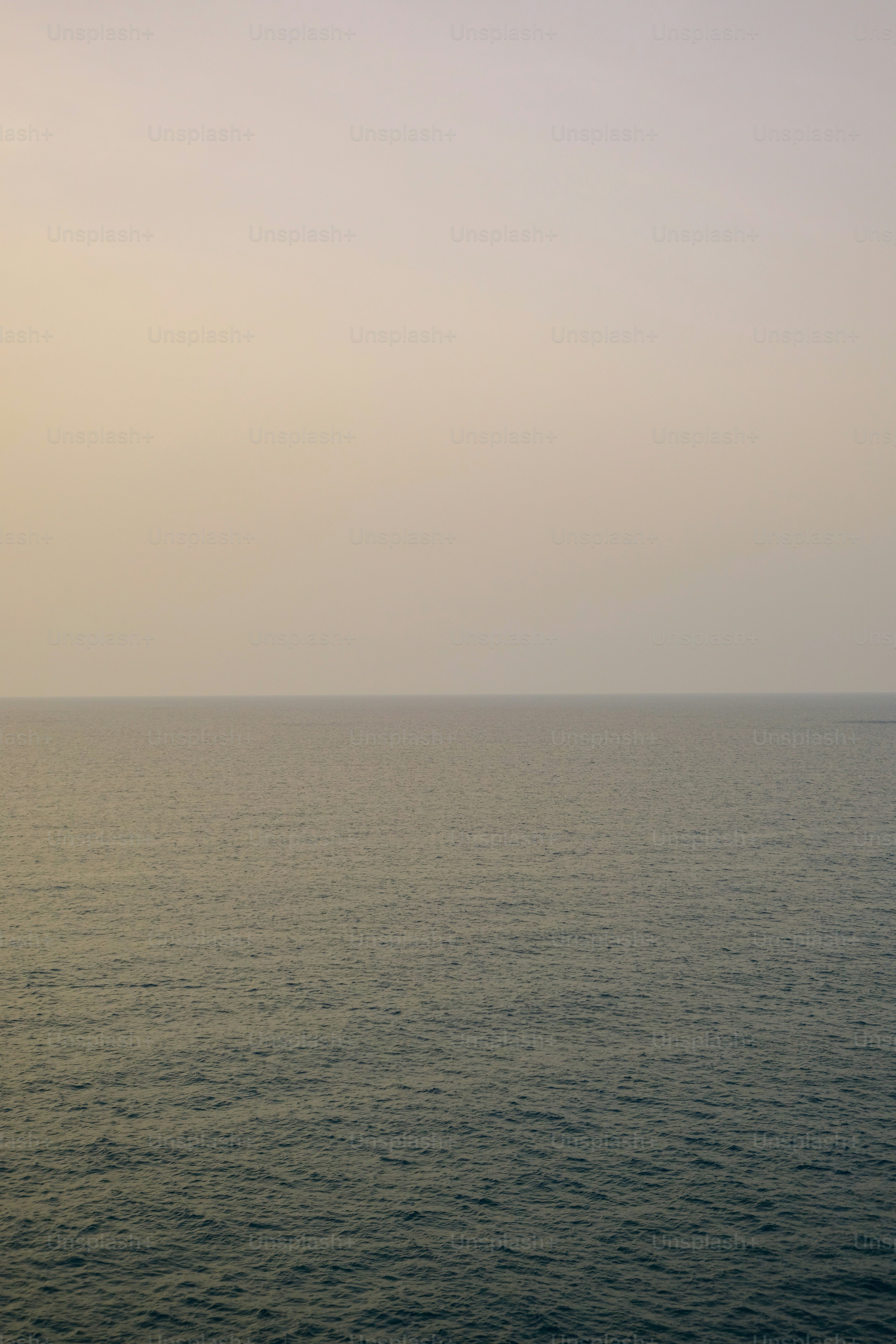 Vast calm ocean under a hazy, muted sky.