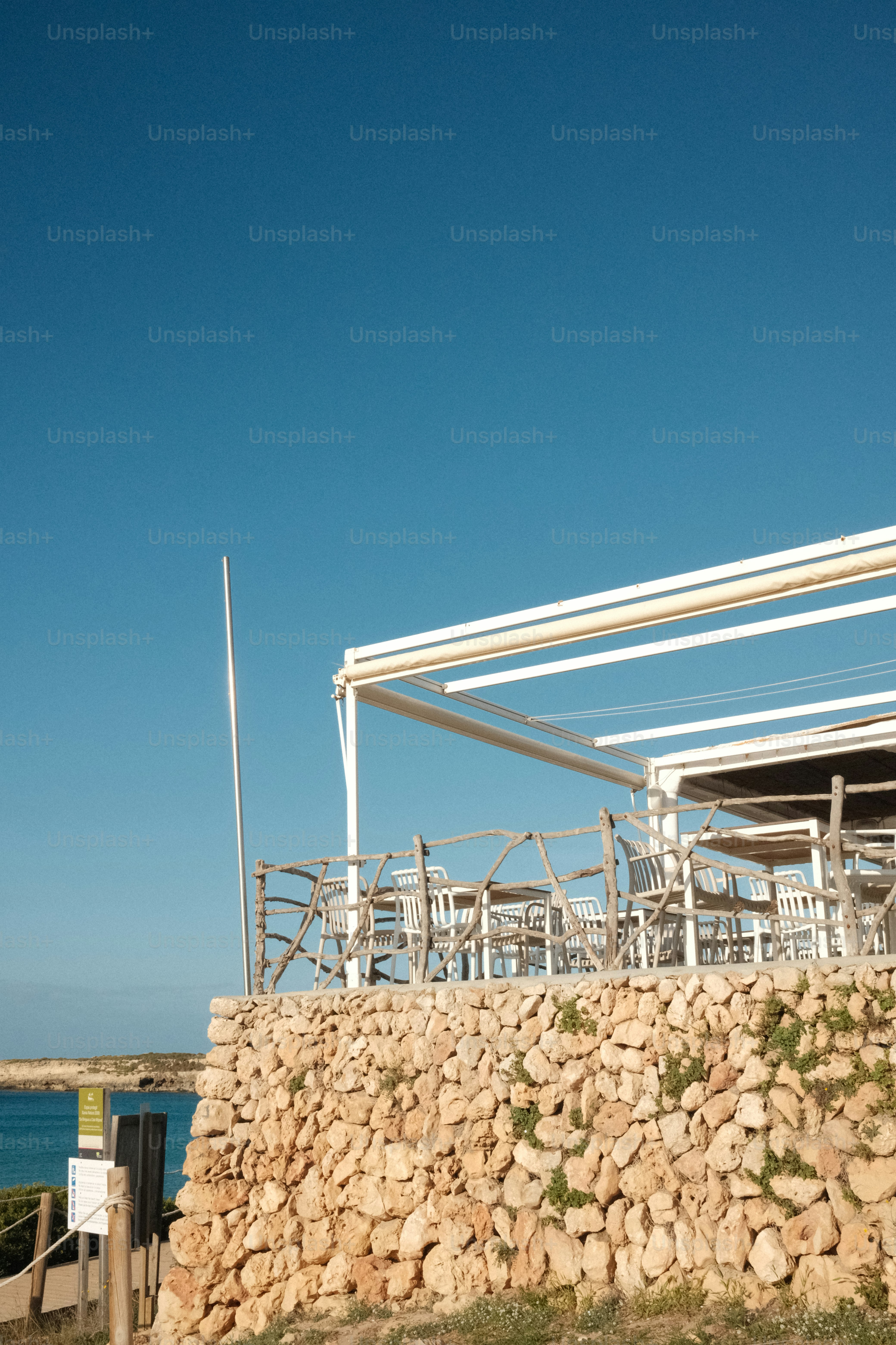 Restaurante costero con muro de piedra y cielo azul.