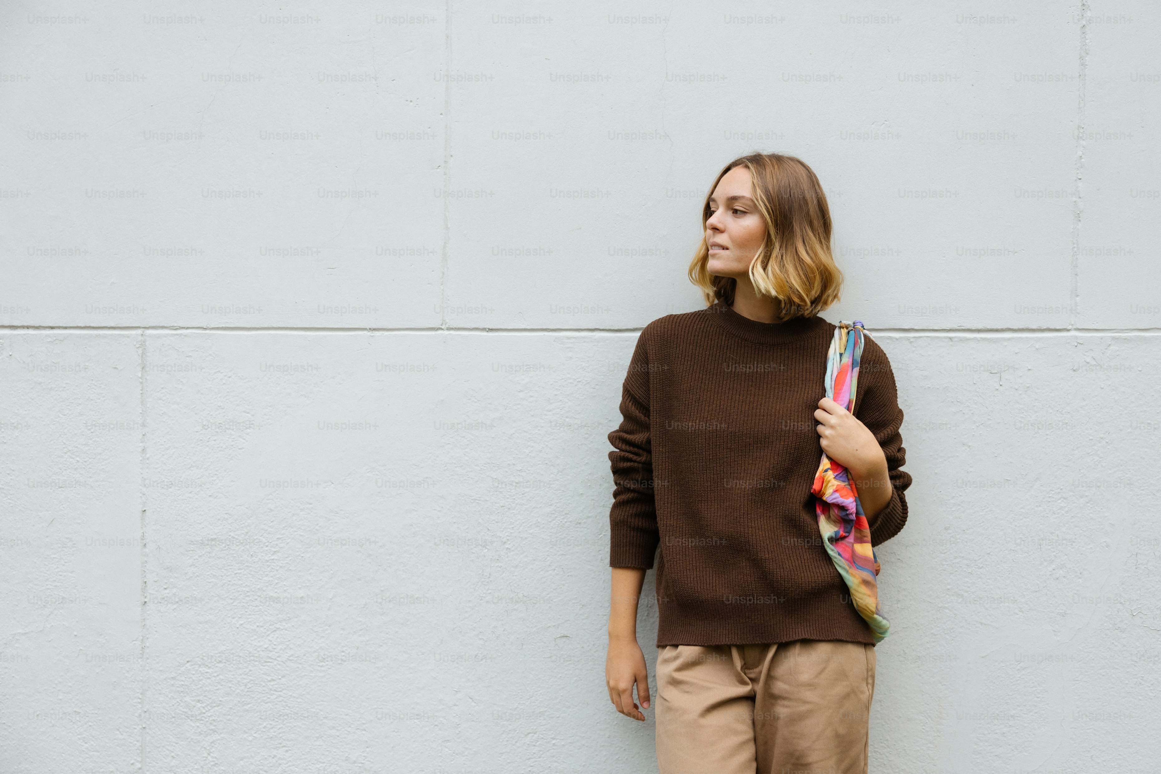 Junge Frau im braunen Pullover mit einer bunten Tasche.