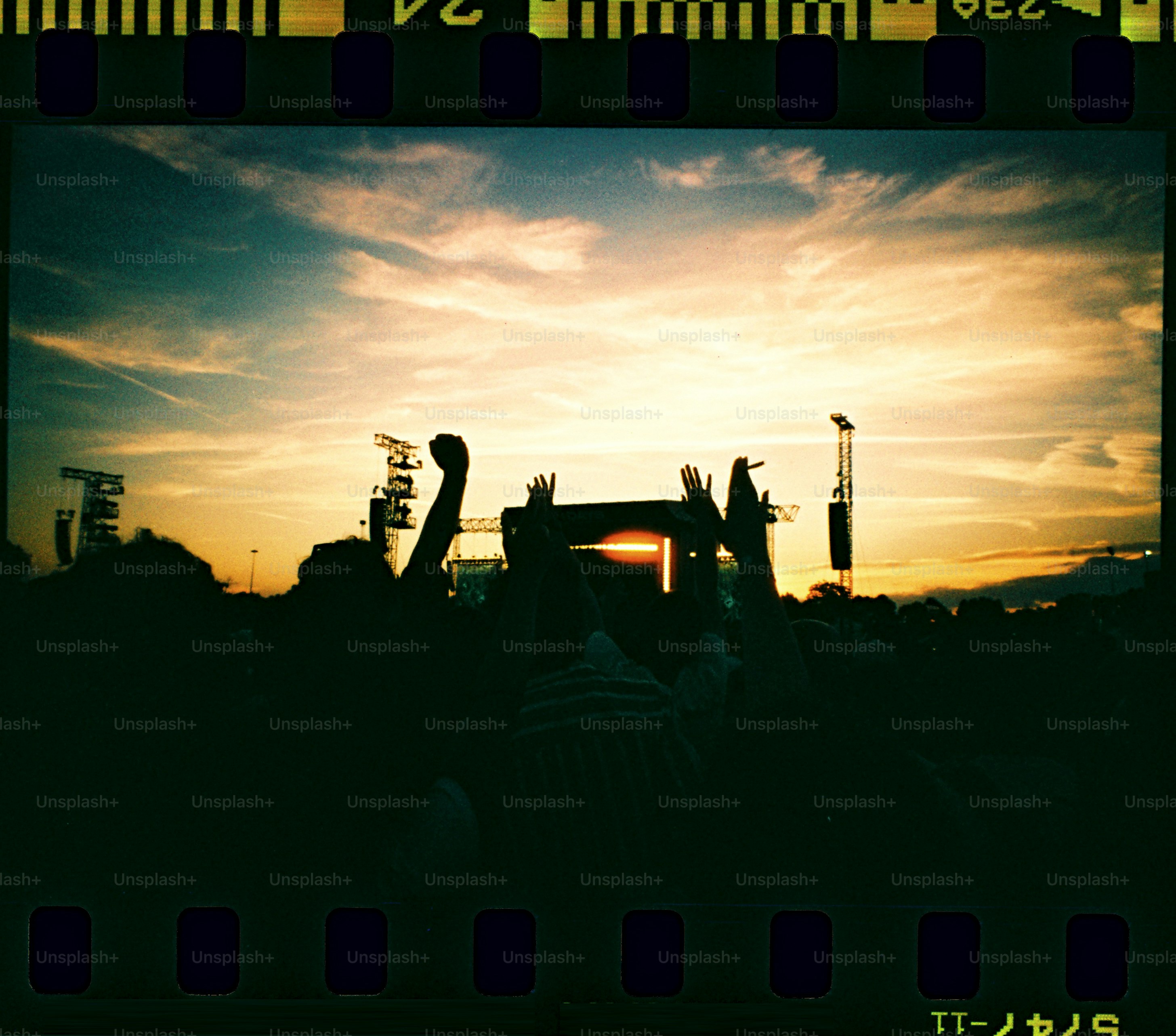夕暮れ時の屋外コンサートで手を挙げる群衆。