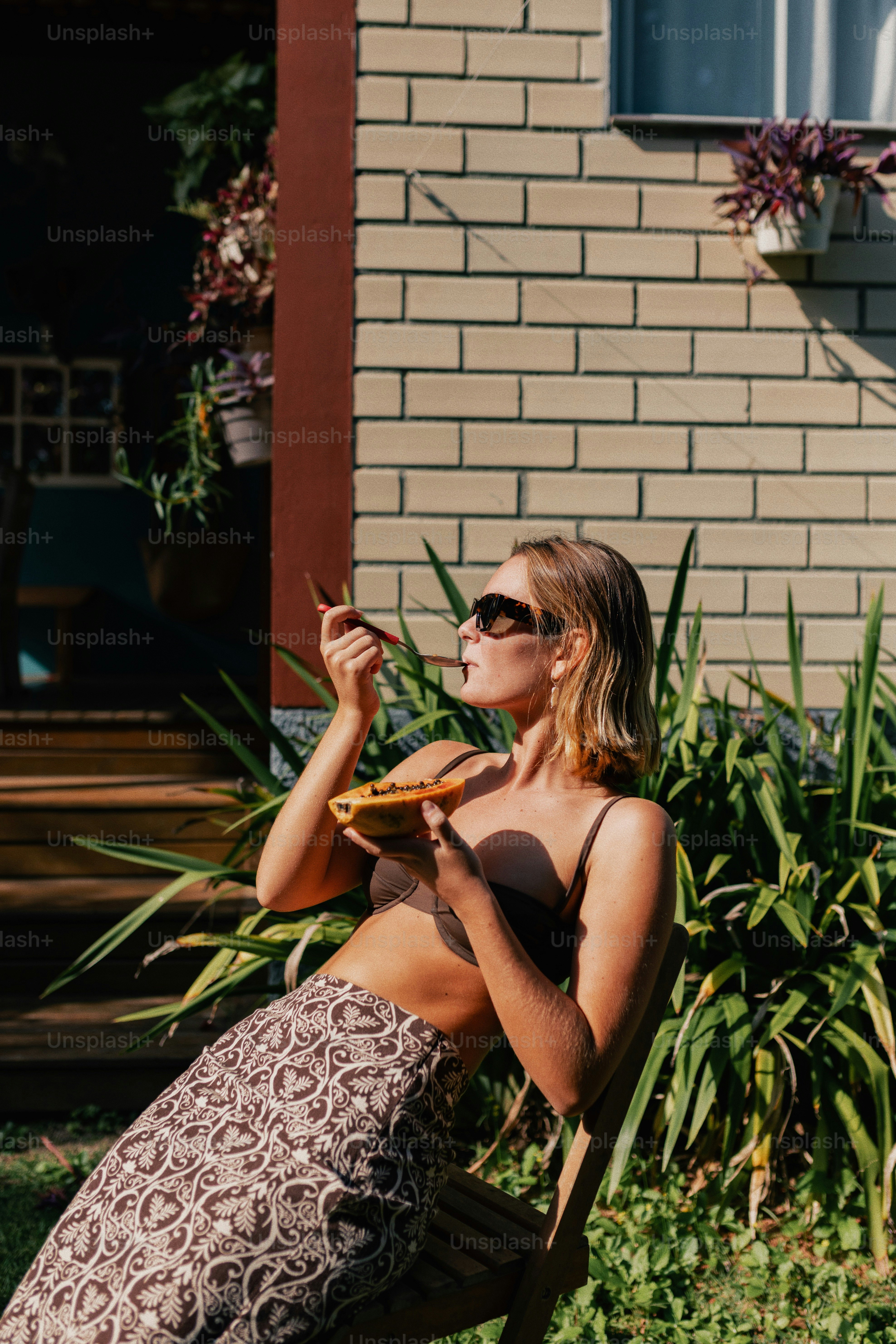 Woman in sunglasses eating a meal outside a house.
