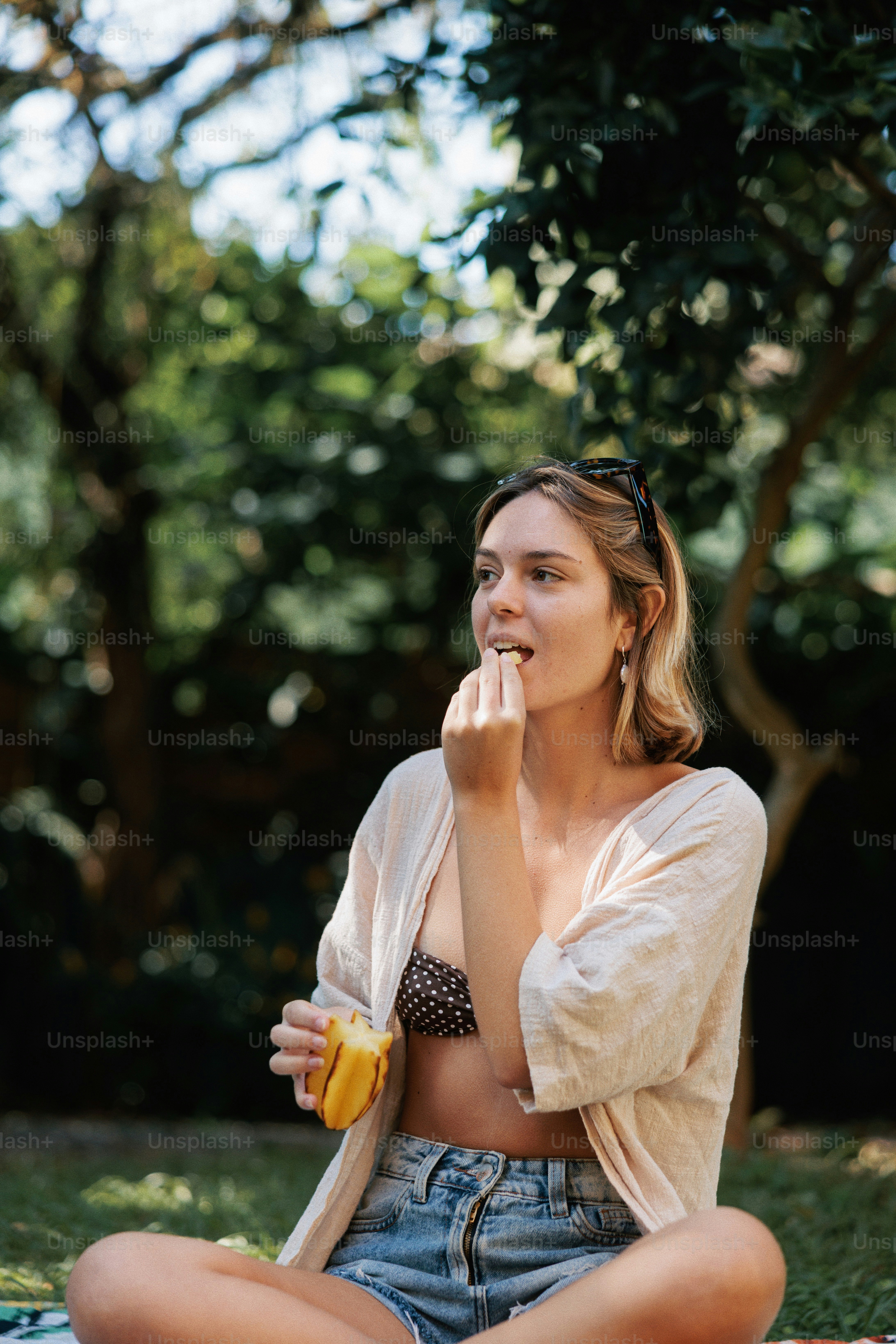 A young woman eating fruit outdoors.