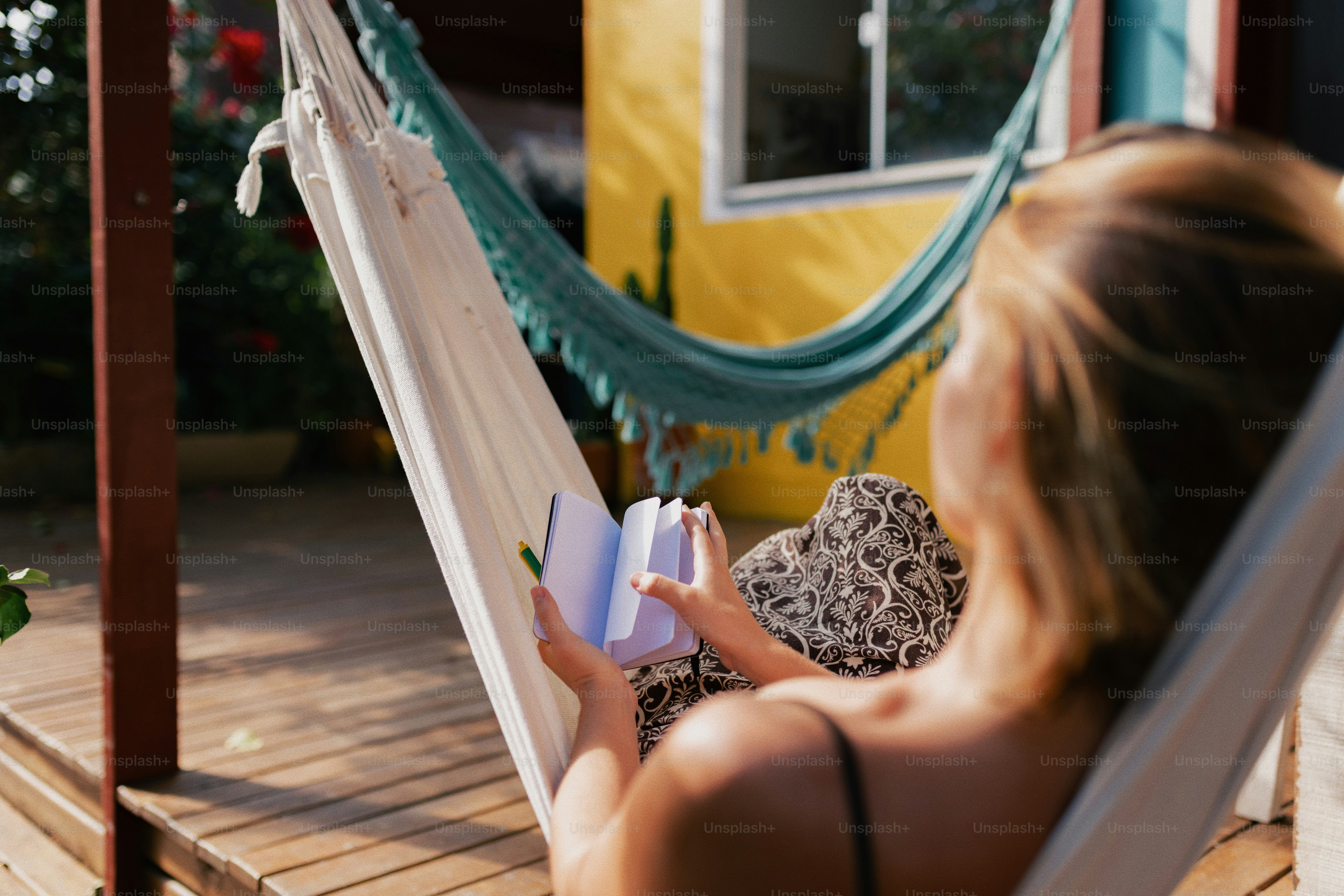 A woman relaxes in a hammock, reading a book outdoors.