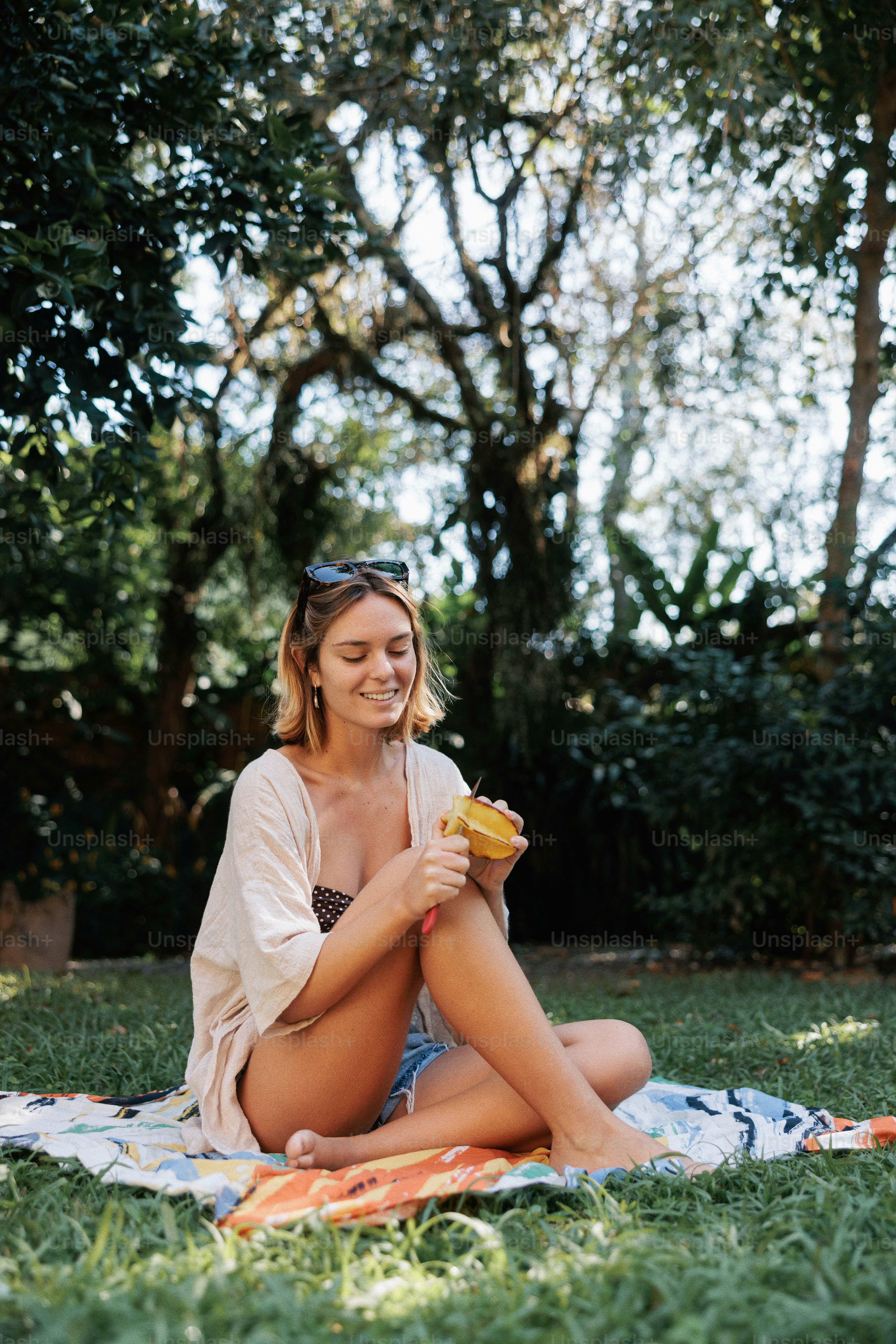 A young woman applies sunscreen to her leg outdoors.