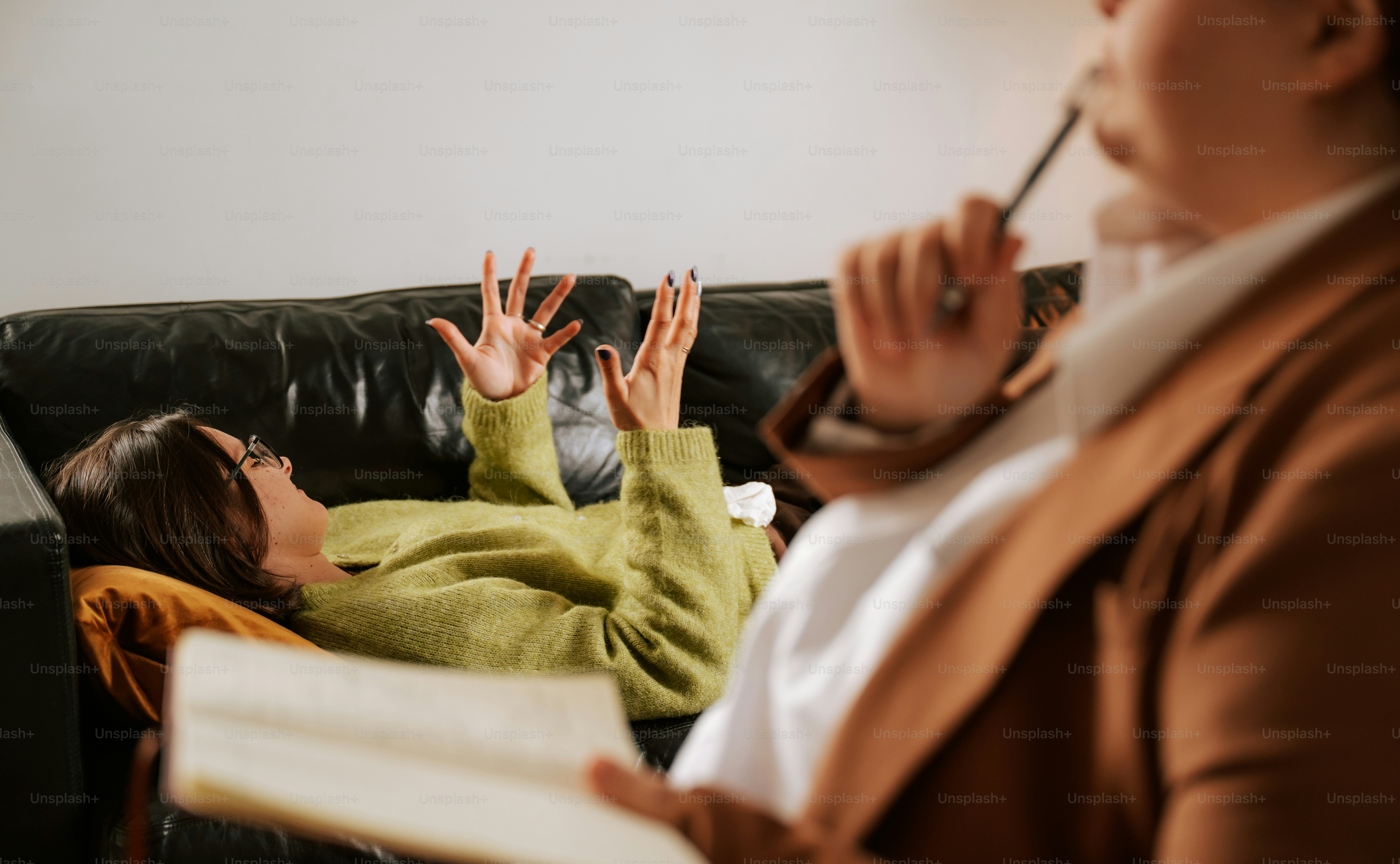 Woman on couch gestures while talking to a therapist.