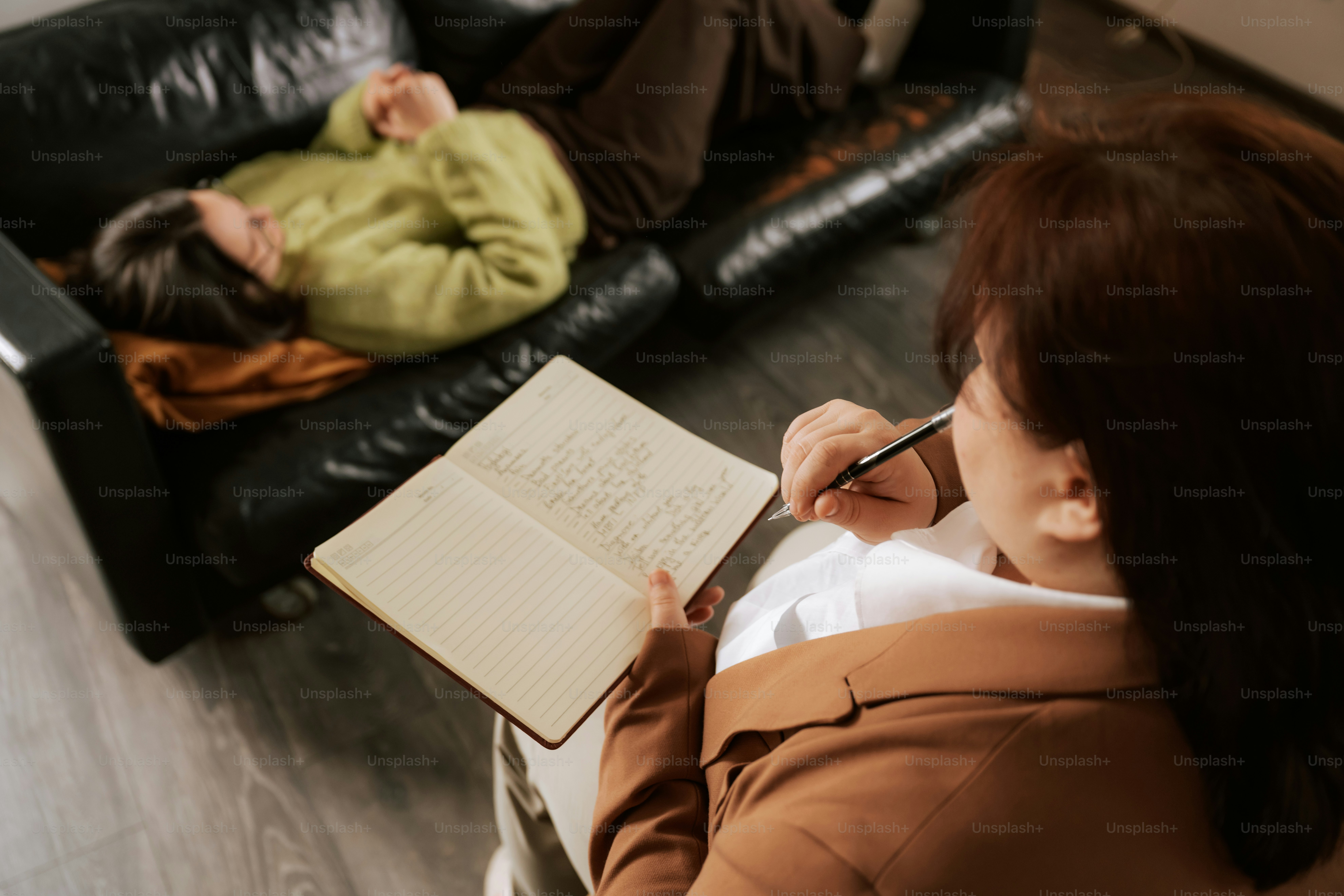 A therapist writes notes during a session with a client.