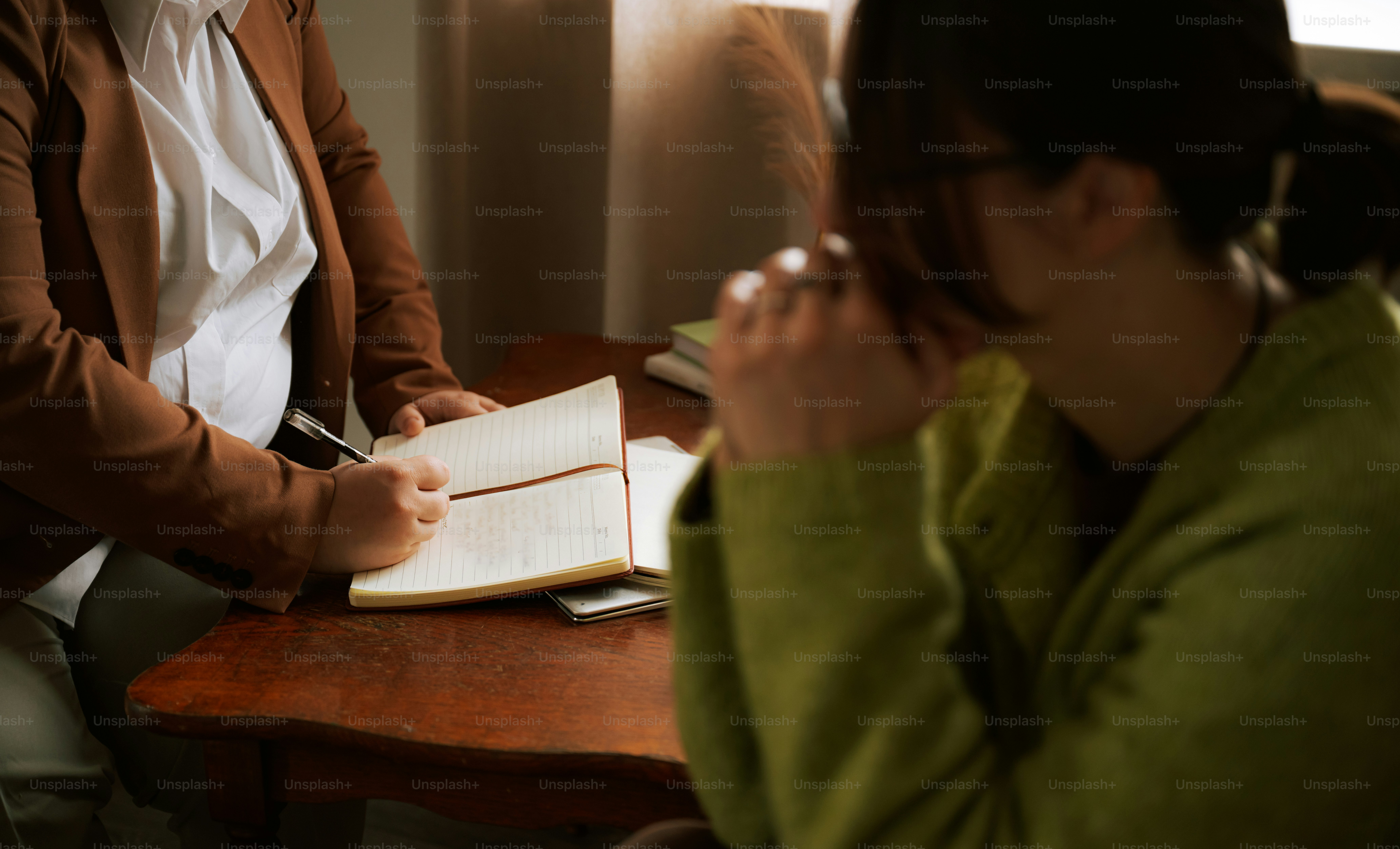 Two people discussing, one writing in a notebook.