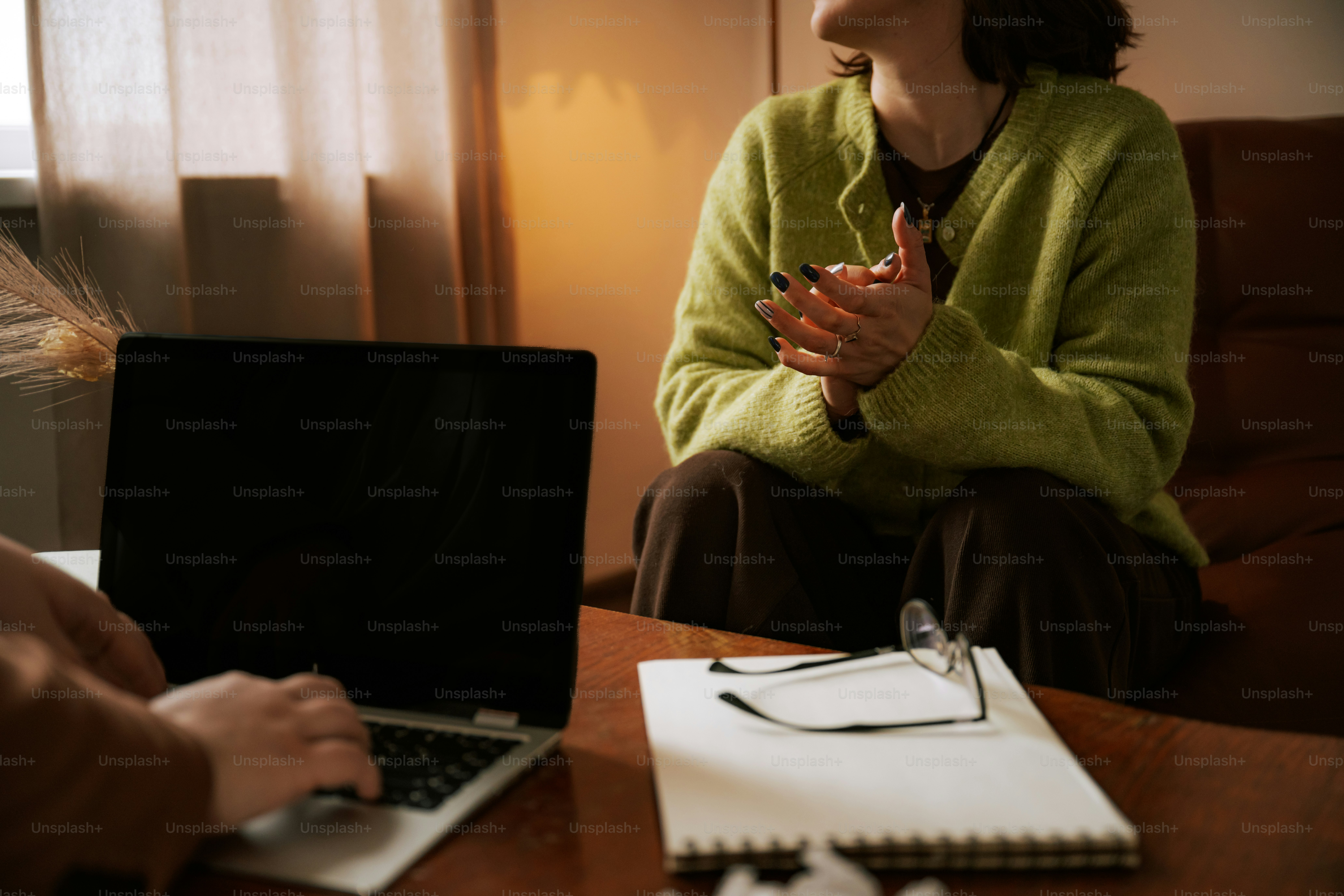 Two individuals having a discussion with a laptop and notepad.