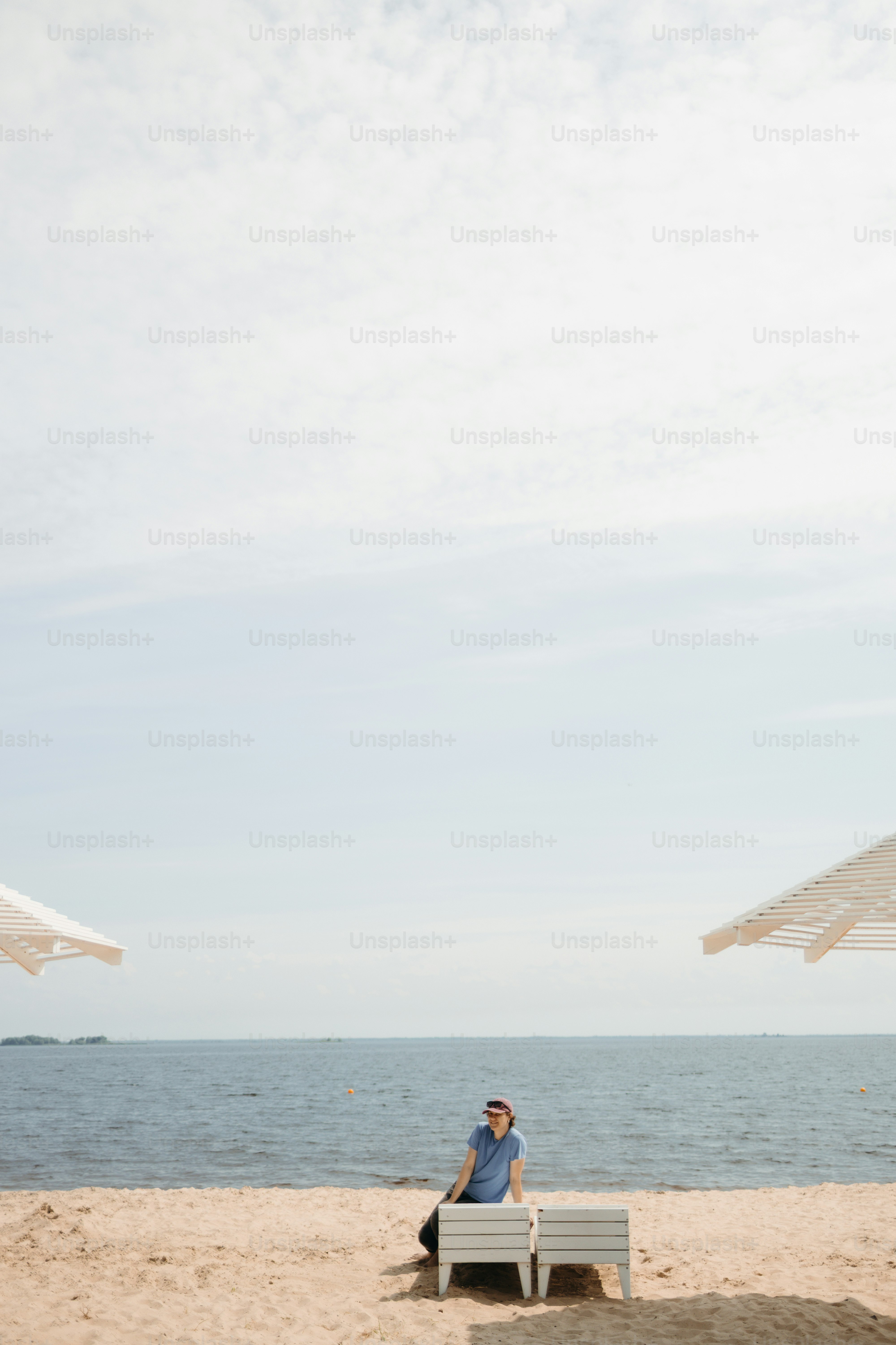 Person relaxing on a beach lounge chair by the ocean.