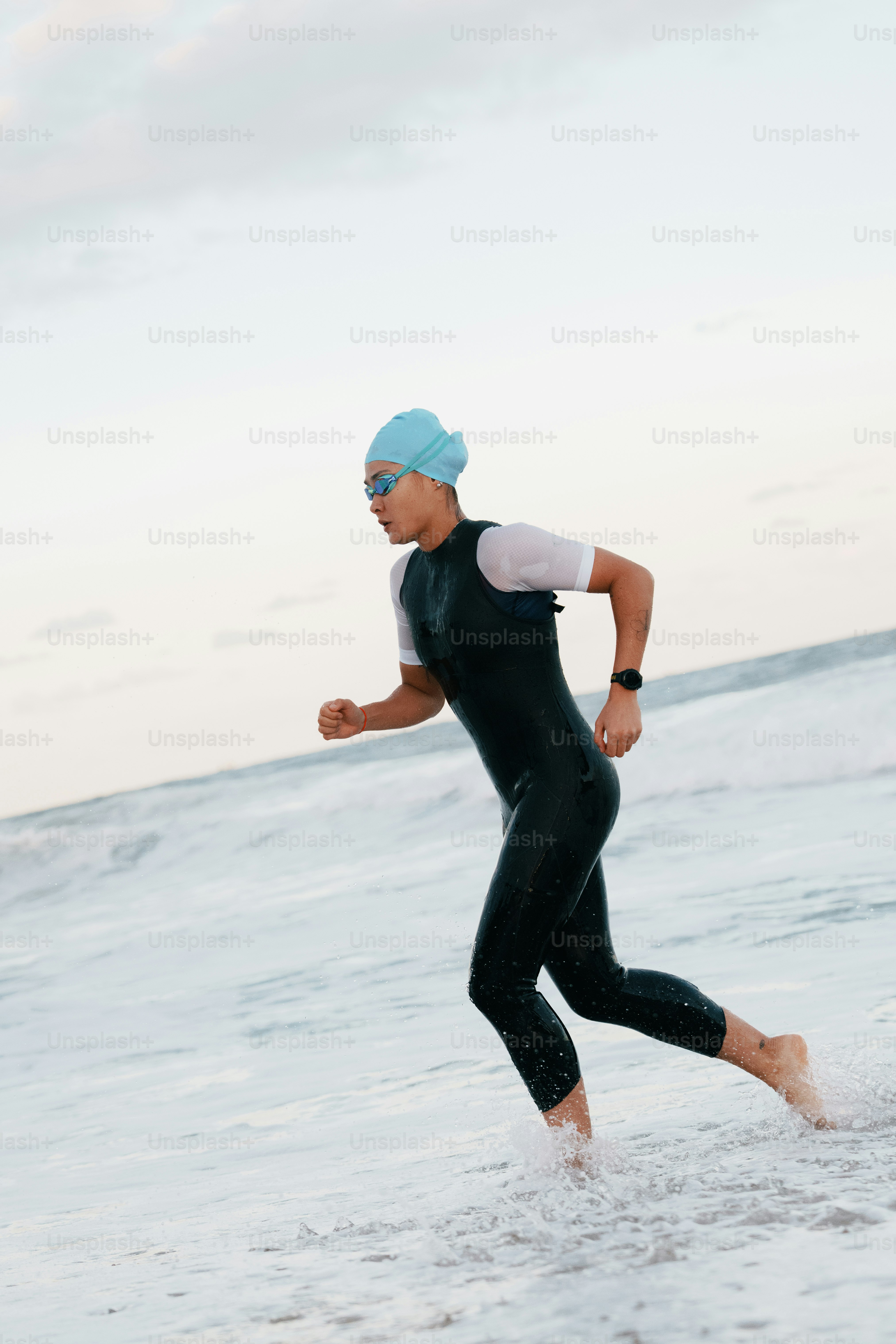 A person in a wetsuit runs through ocean waves.