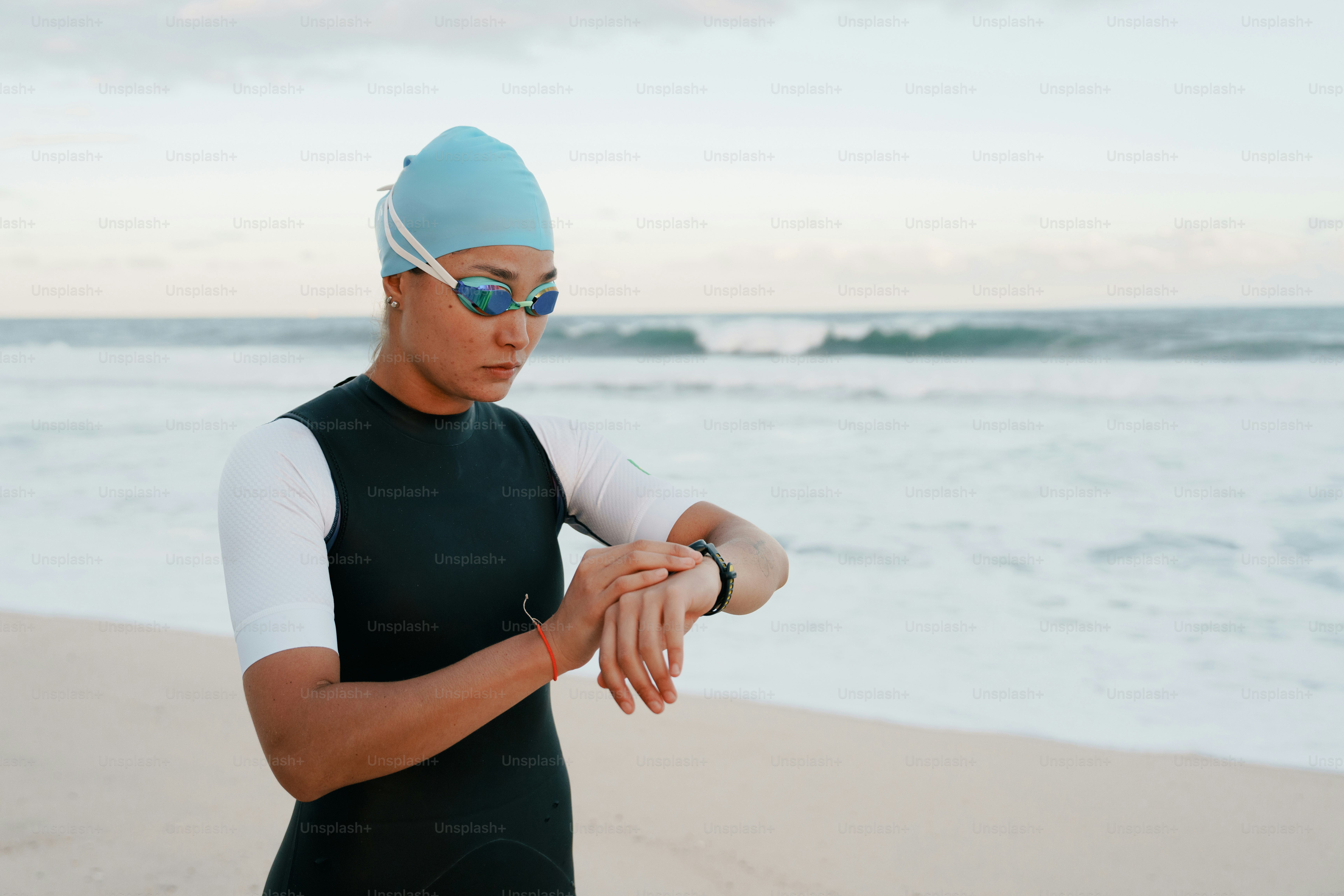 A swimmer checks her smartwatch on a beach