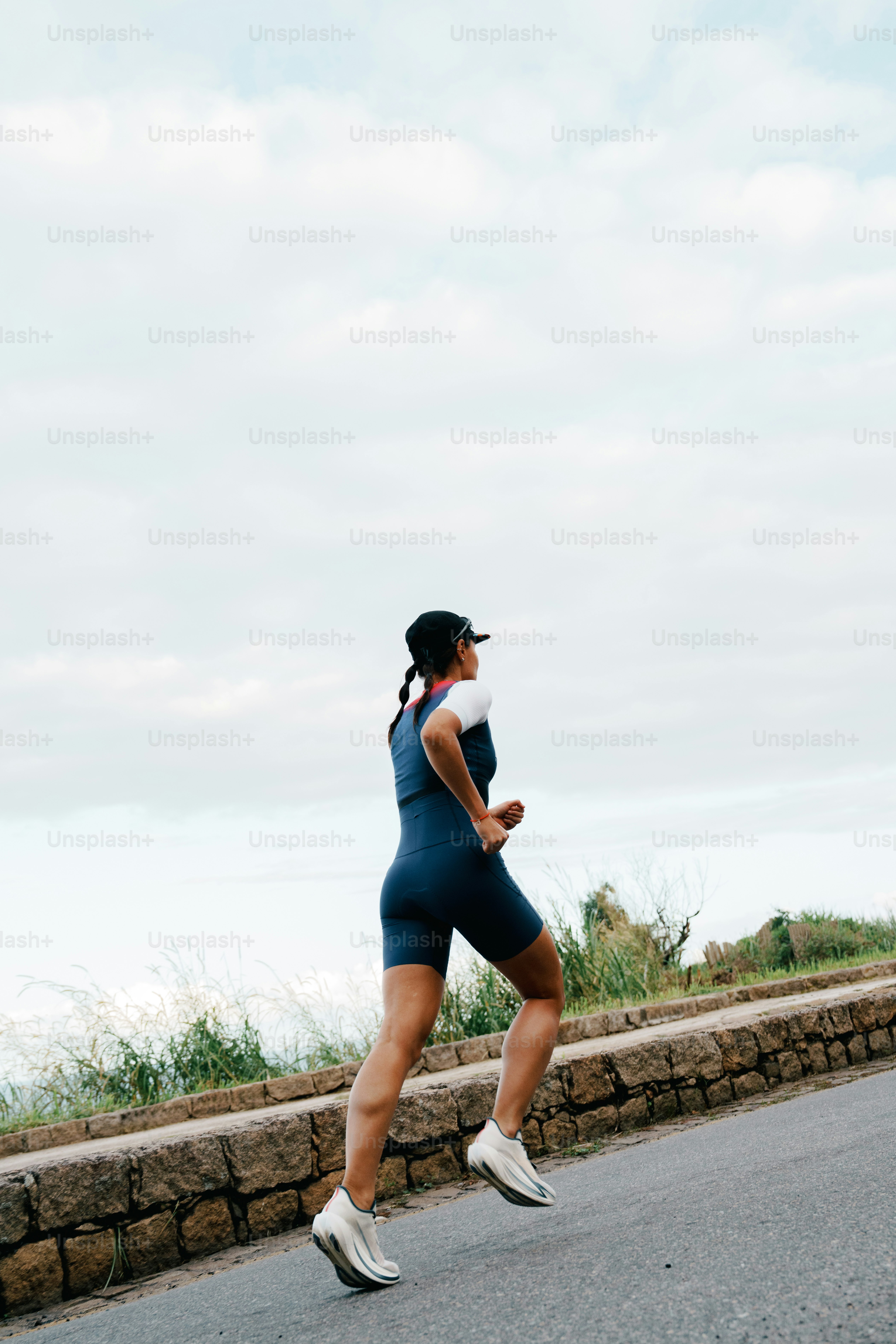 Woman running uphill on a road.