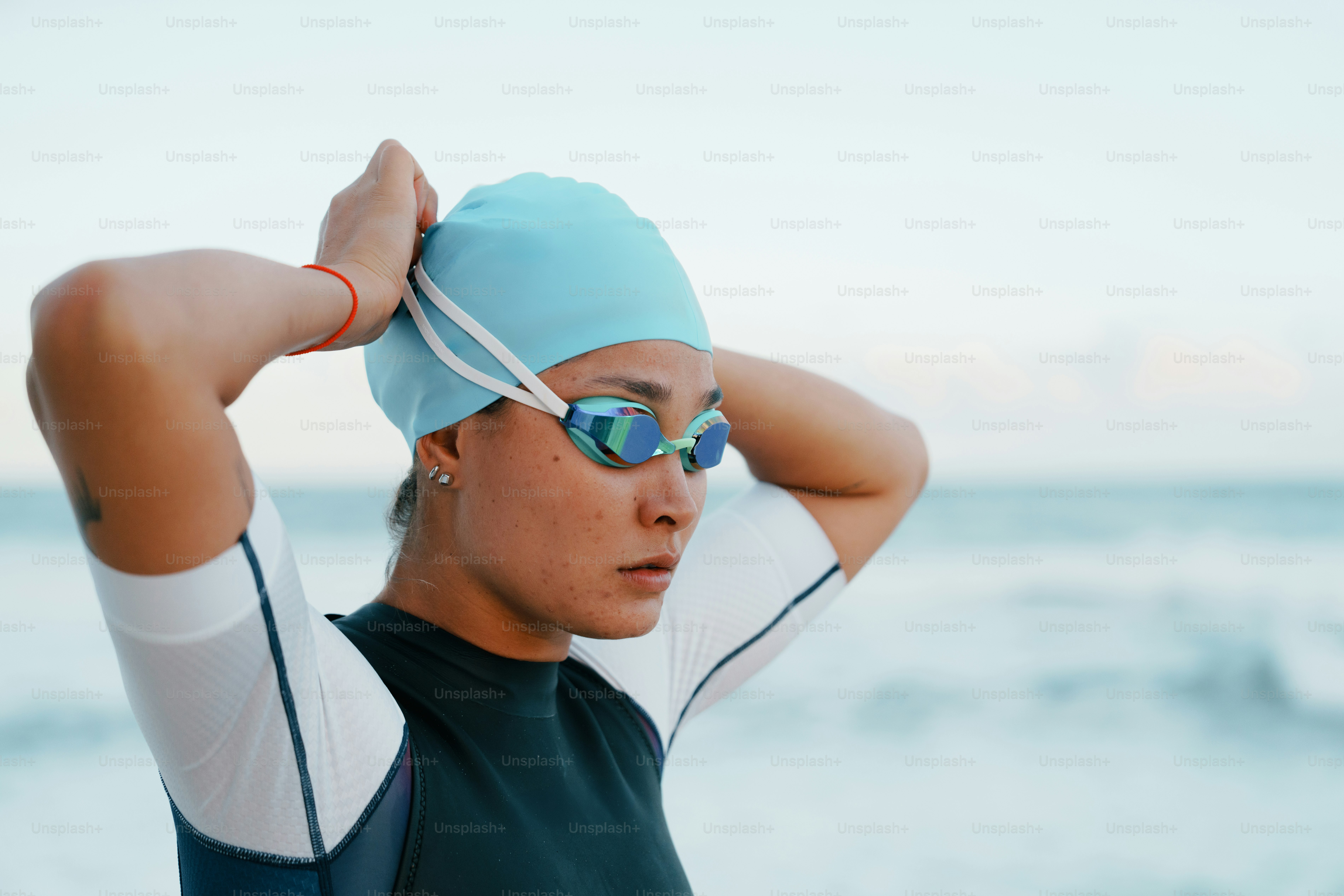 Female swimmer adjusting her blue cap and goggles