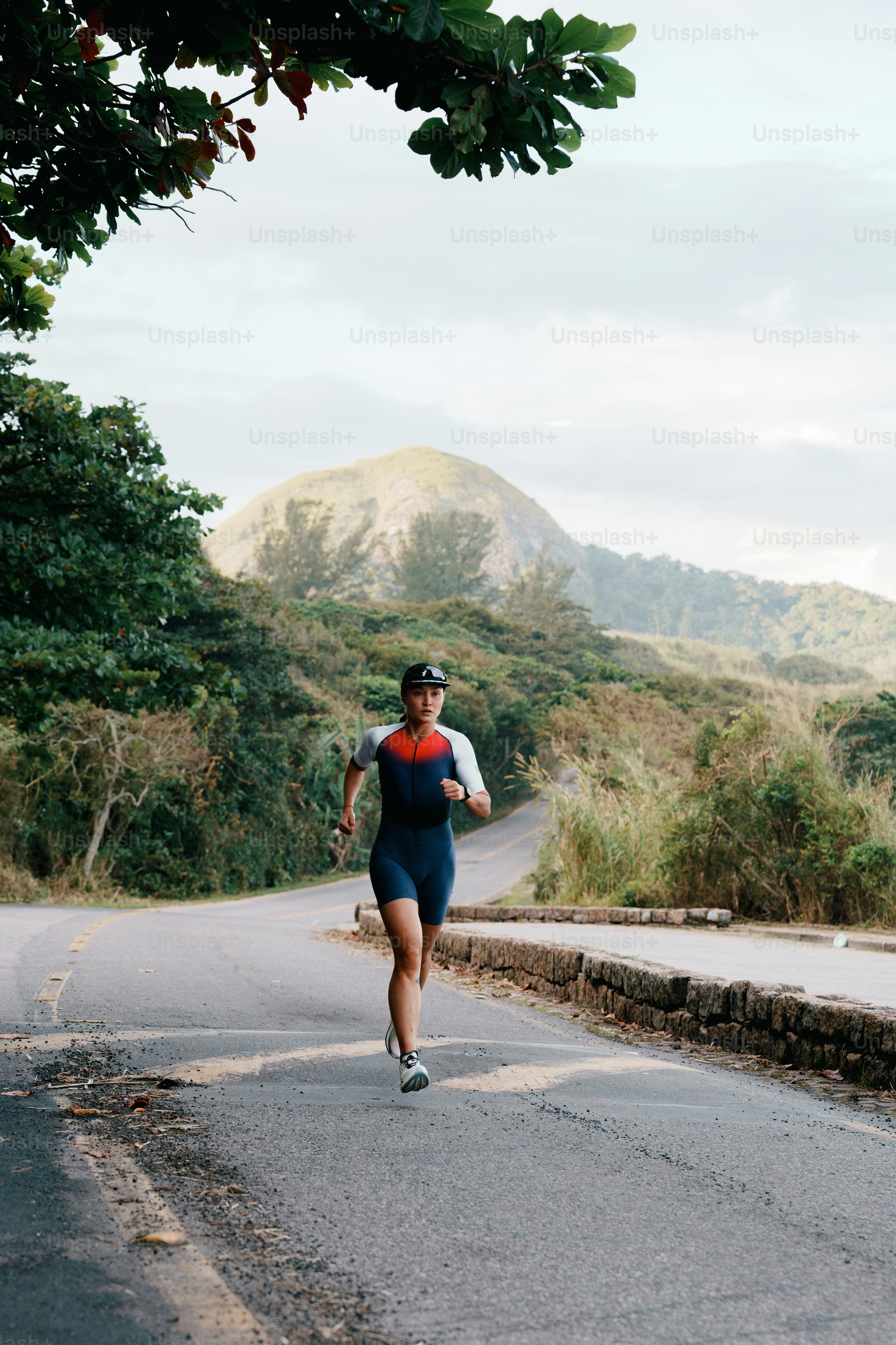 A woman runs on a road amidst mountains.