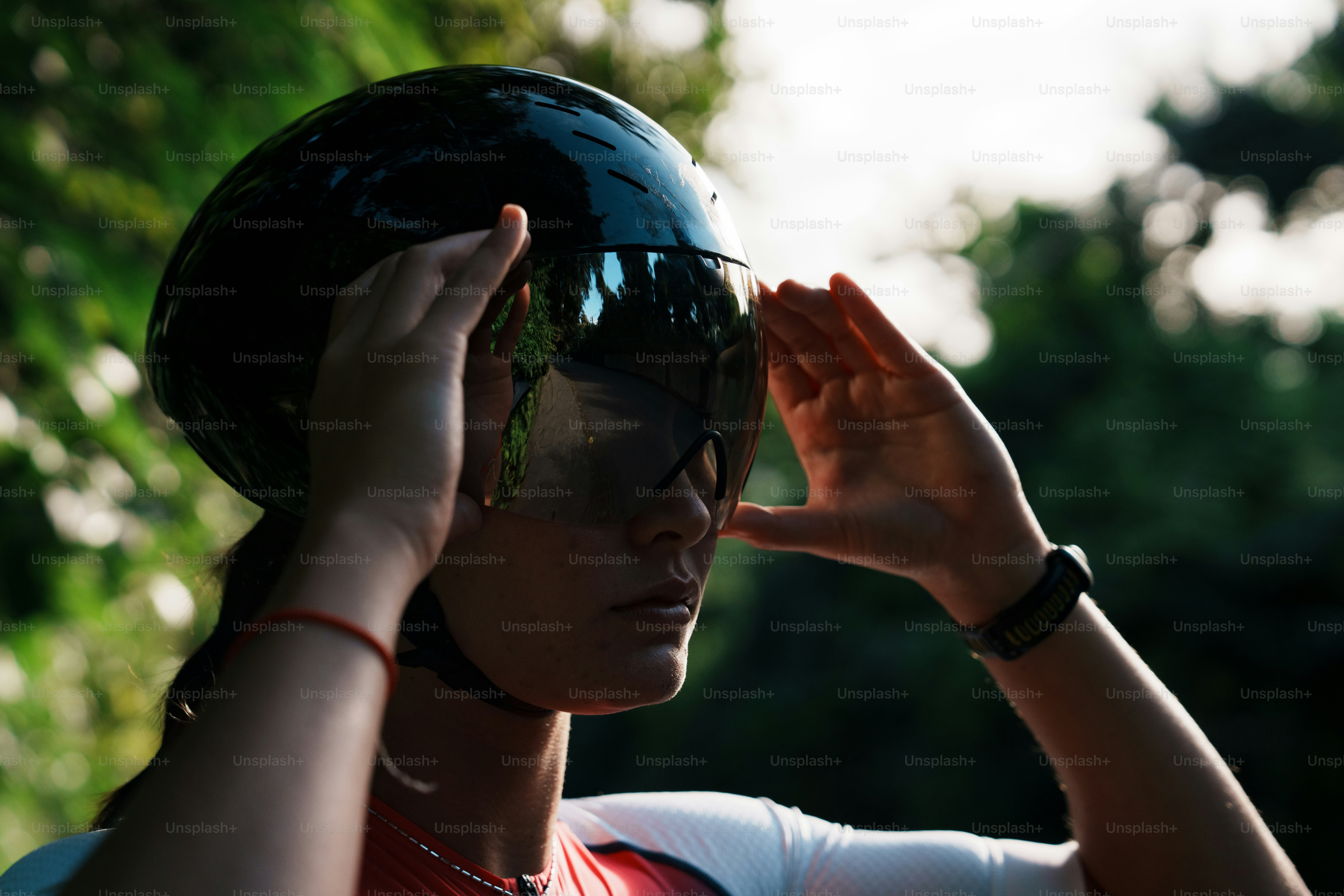 A woman adjusts her cycling helmet visor outdoors