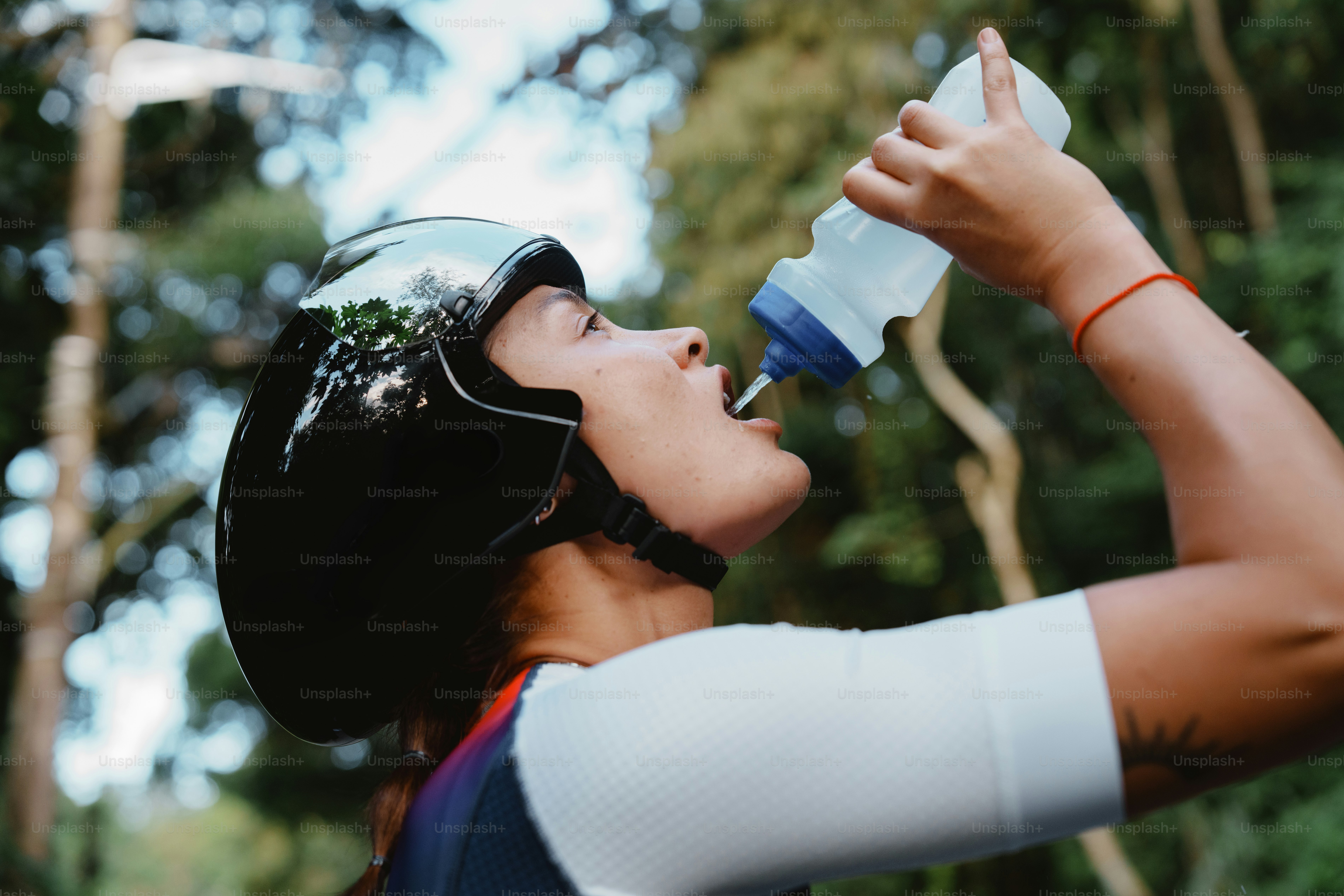 Cyclist in helmet drinks water outdoors