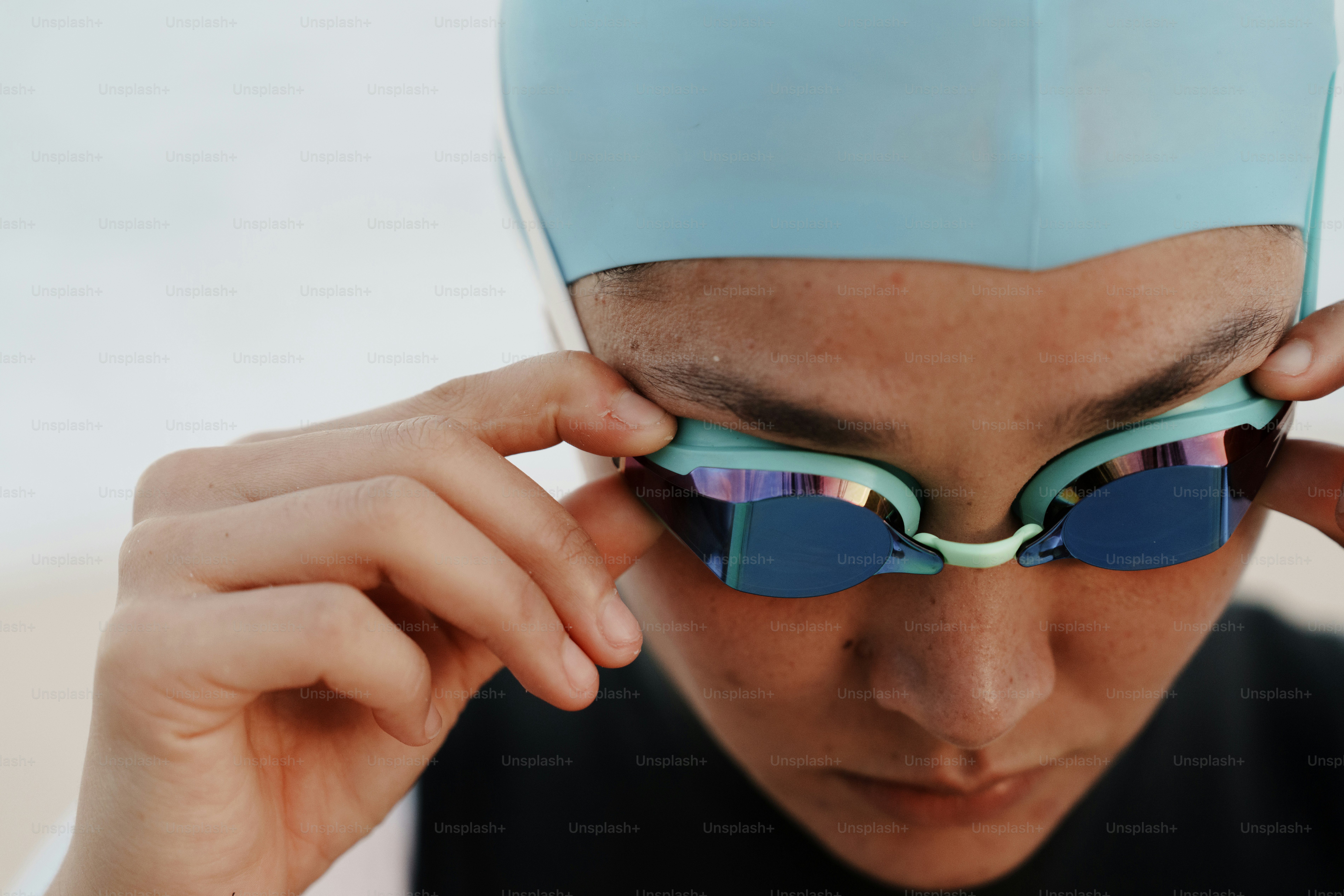Woman adjusting her blue swimming goggles.