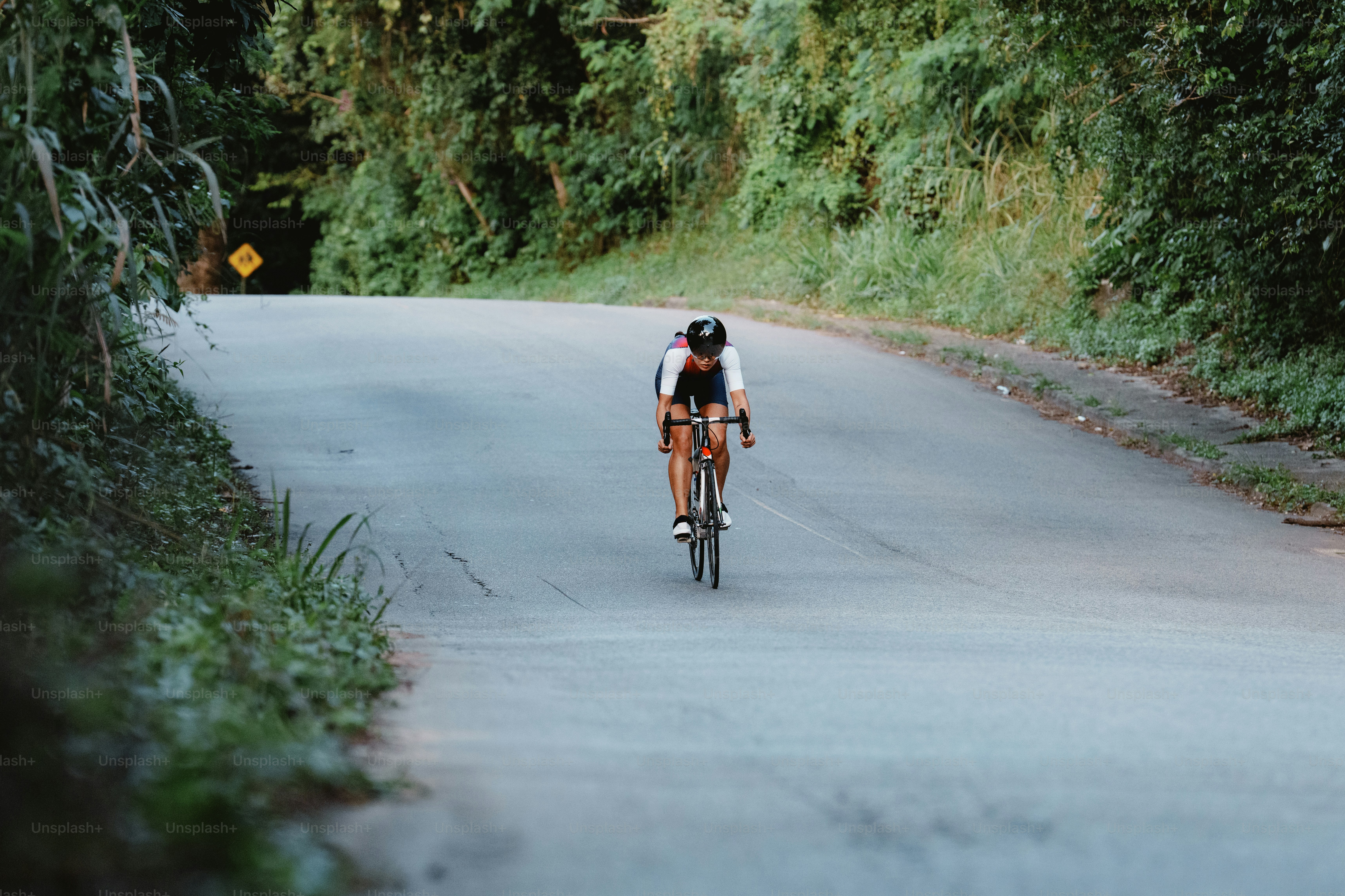 A person rides a bicycle uphill on a winding road.
