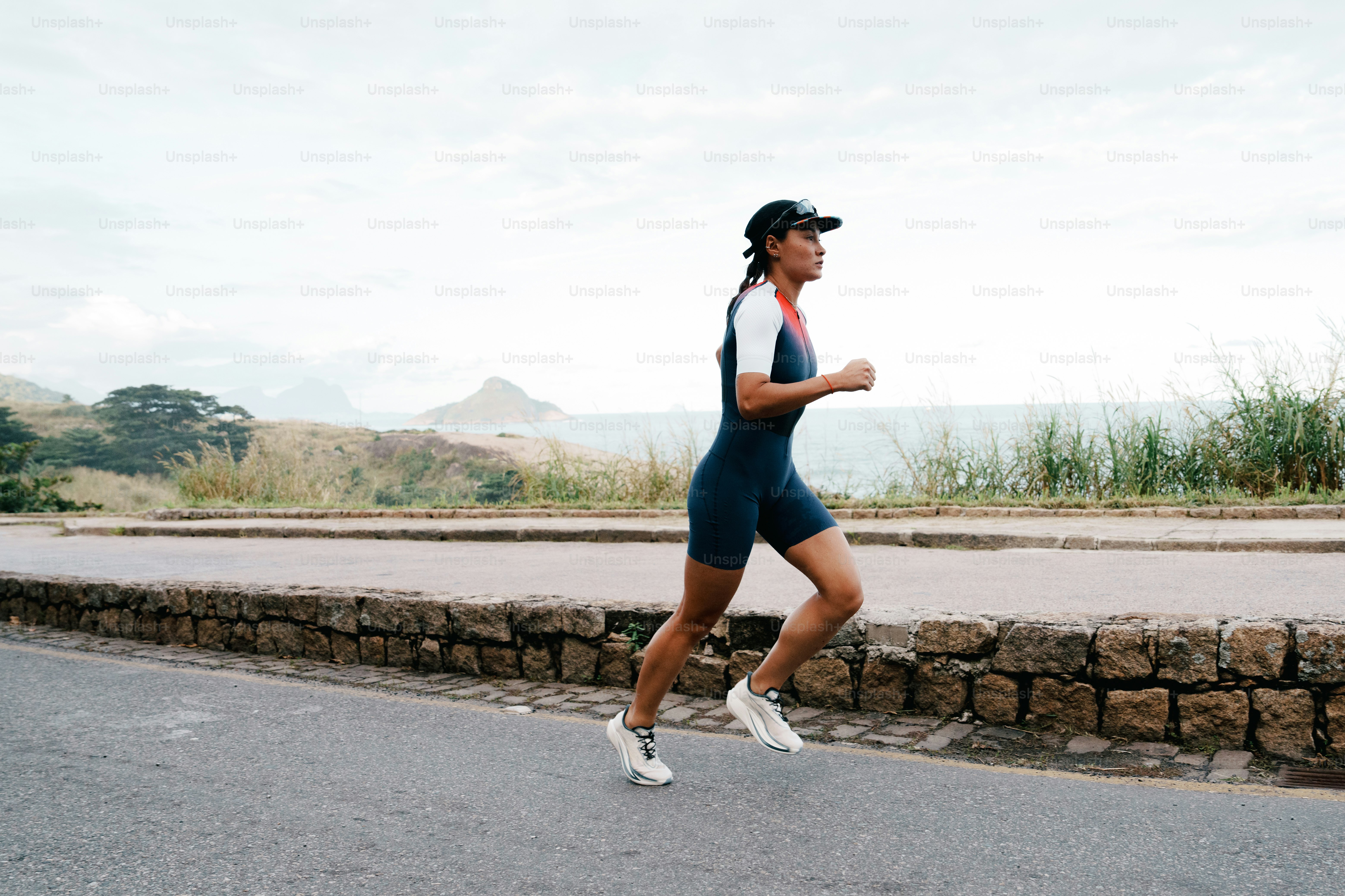 A woman running outdoors along a coastal road.