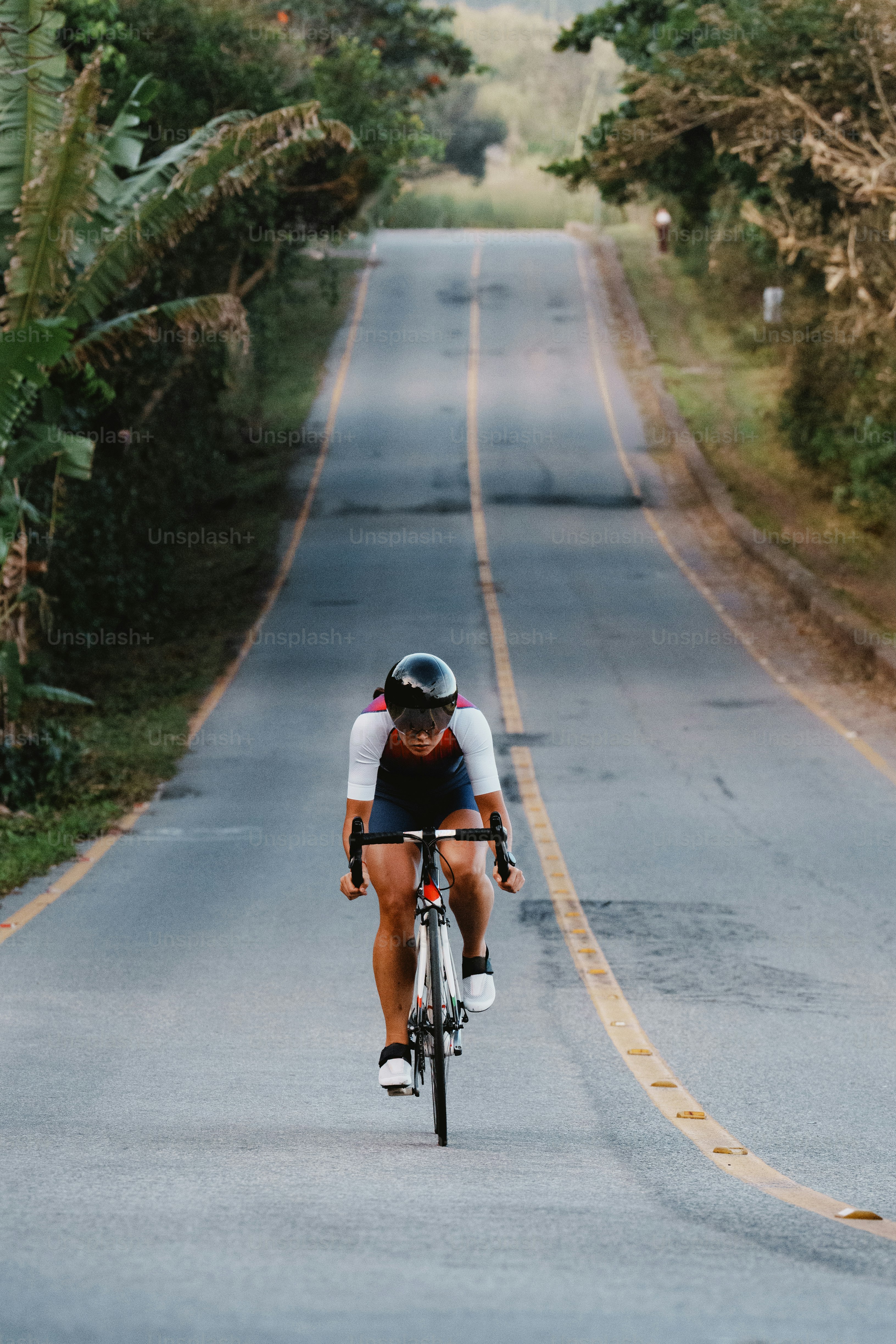 A person cycling uphill on a winding road.