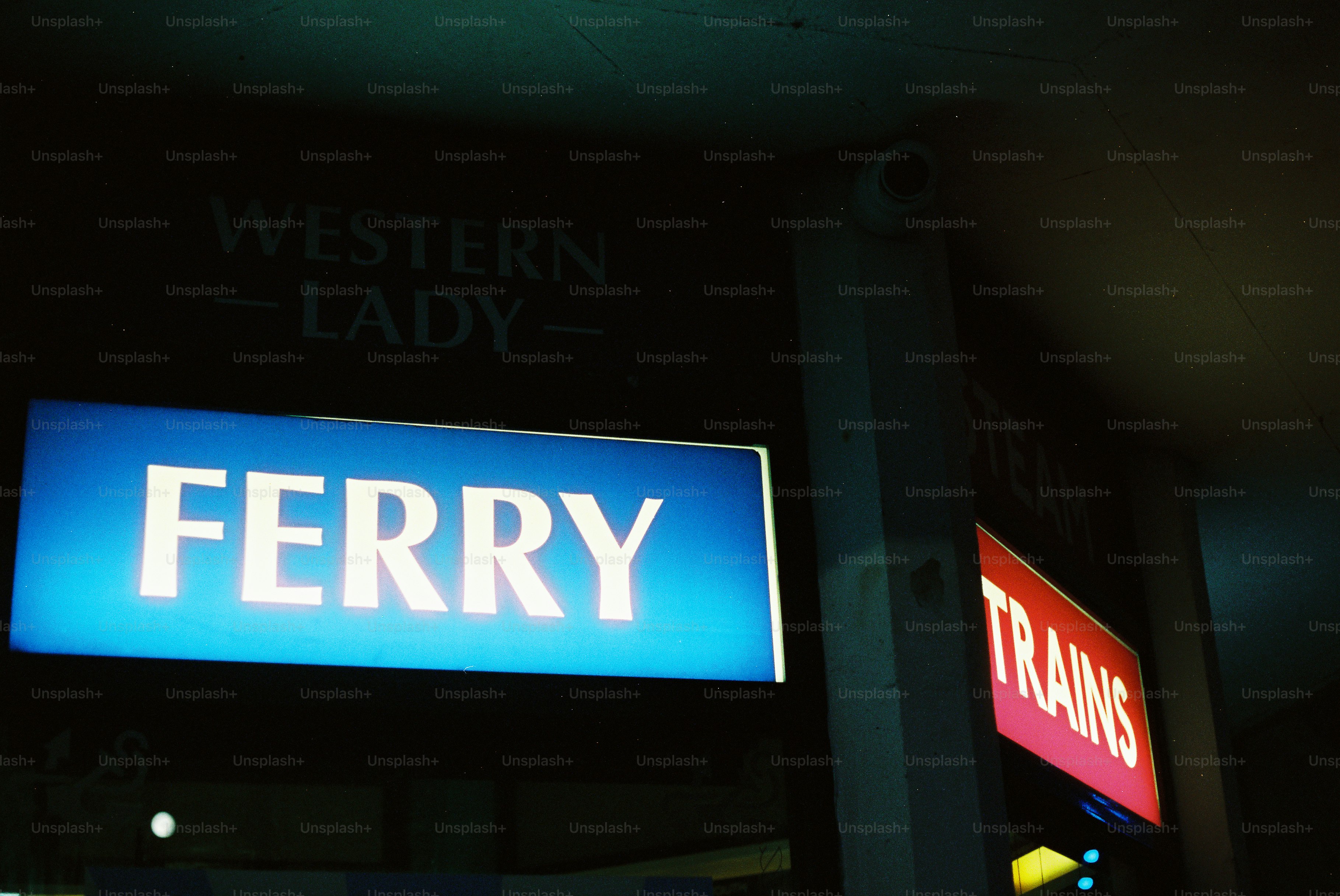 Illuminated "ferry" and "trains" signs at night