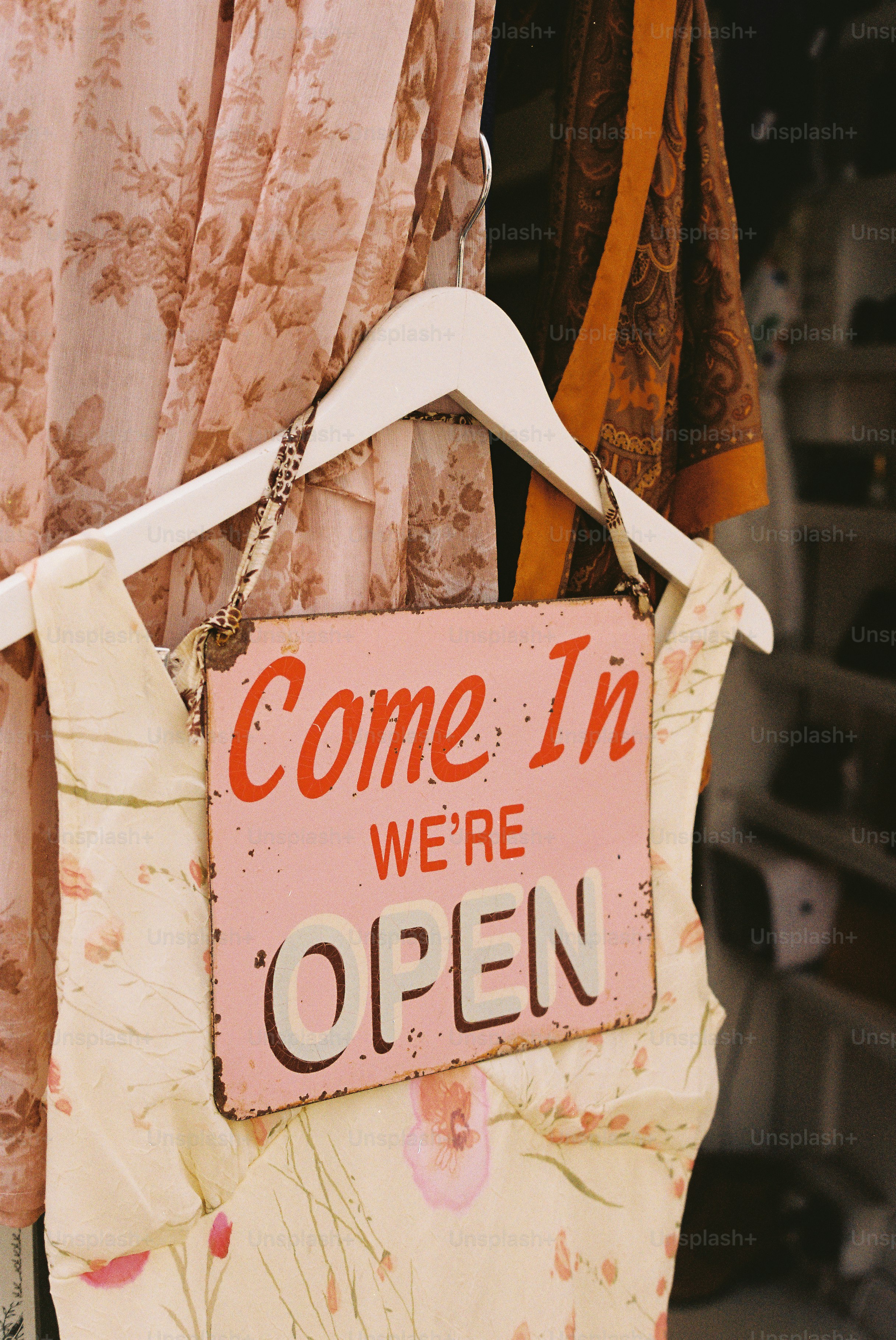 A "come in we're open" sign hangs on a dress