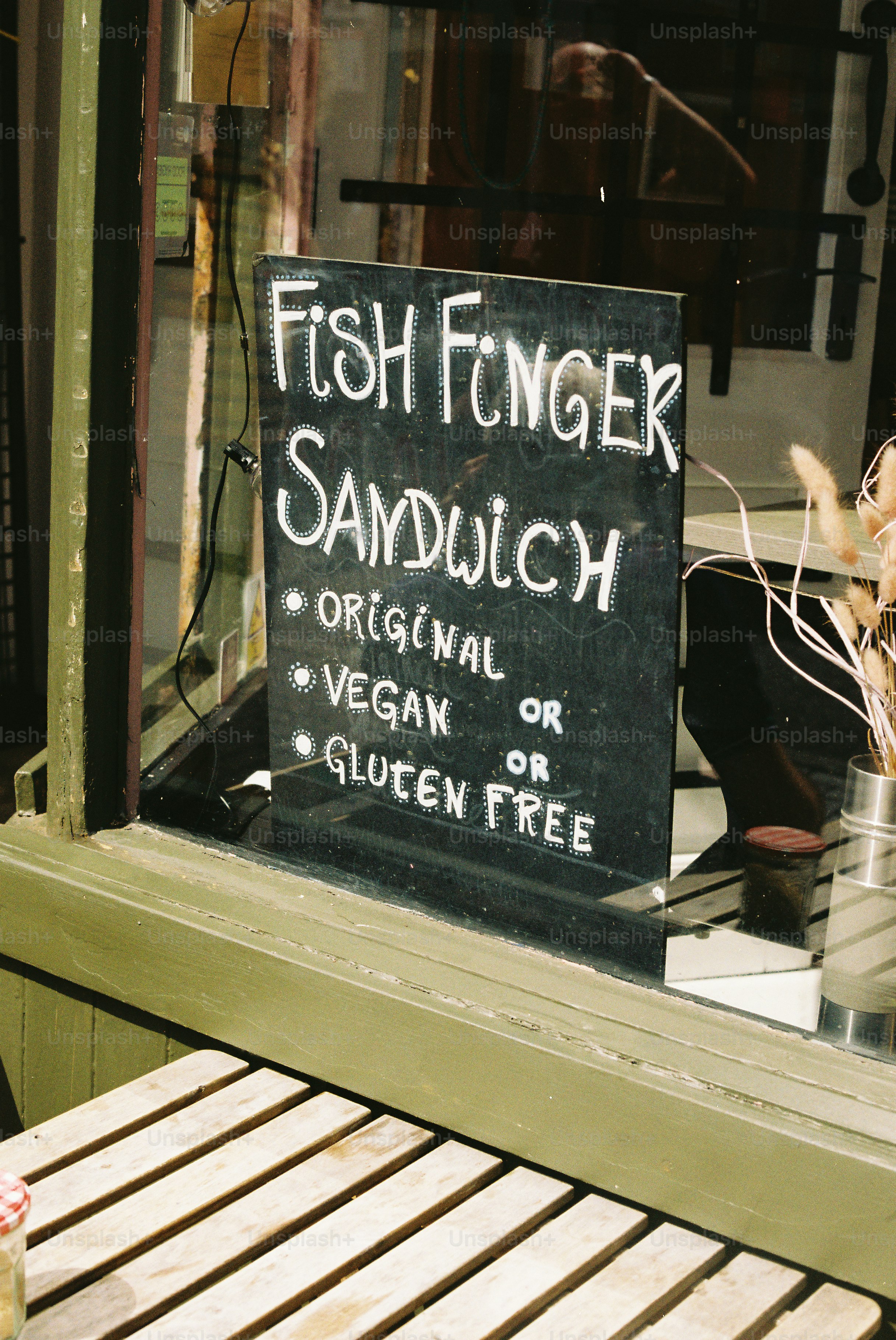 A blackboard sign advertises fish finger sandwiches in a window.