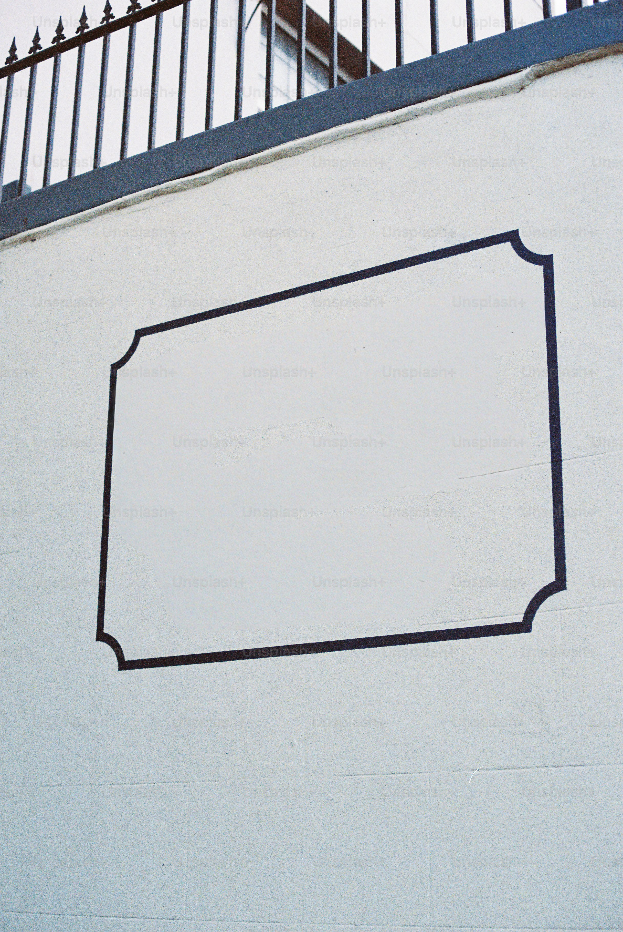 Empty black frame on a white wall with a railing.