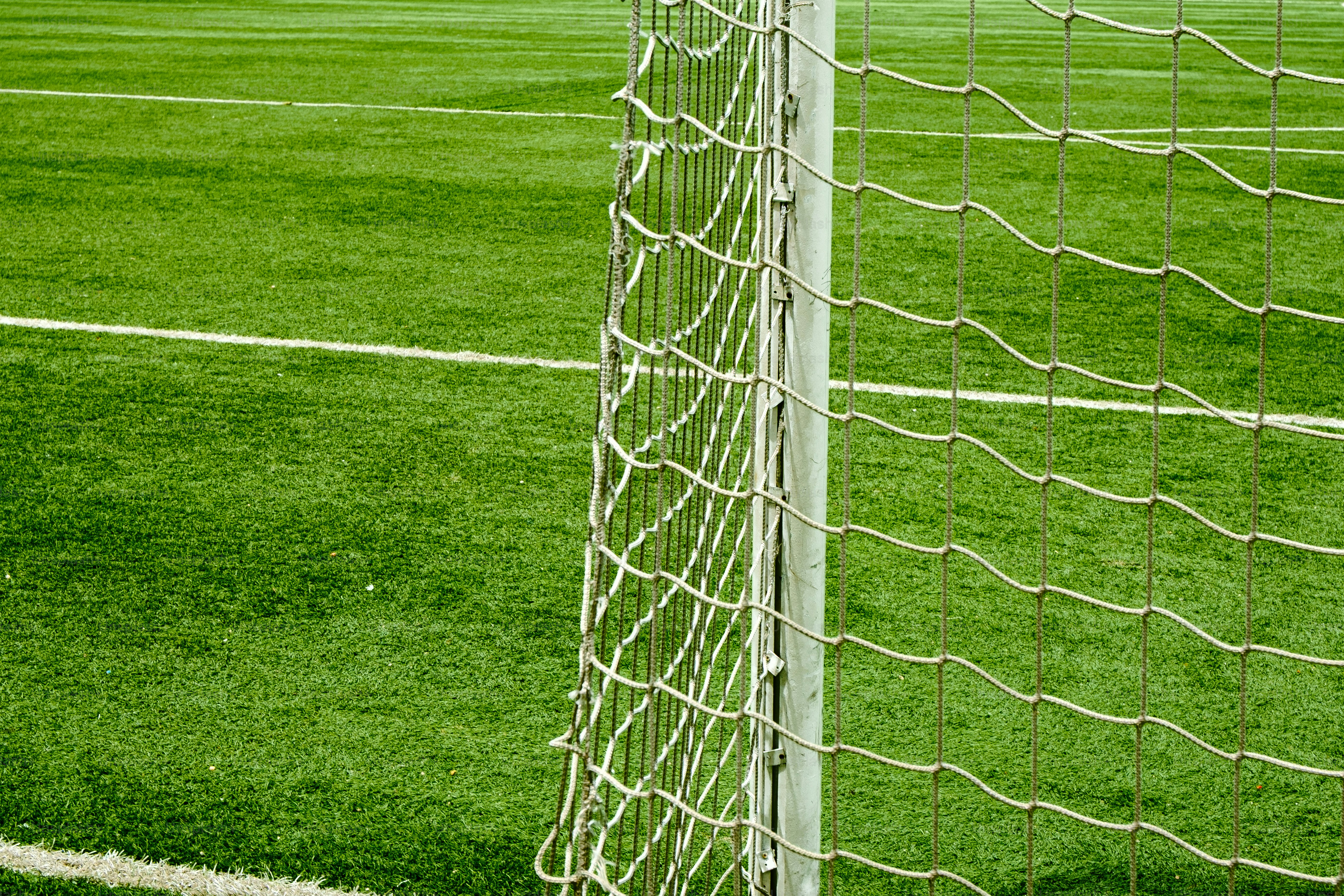 Soccer goal net and green artificial turf field.