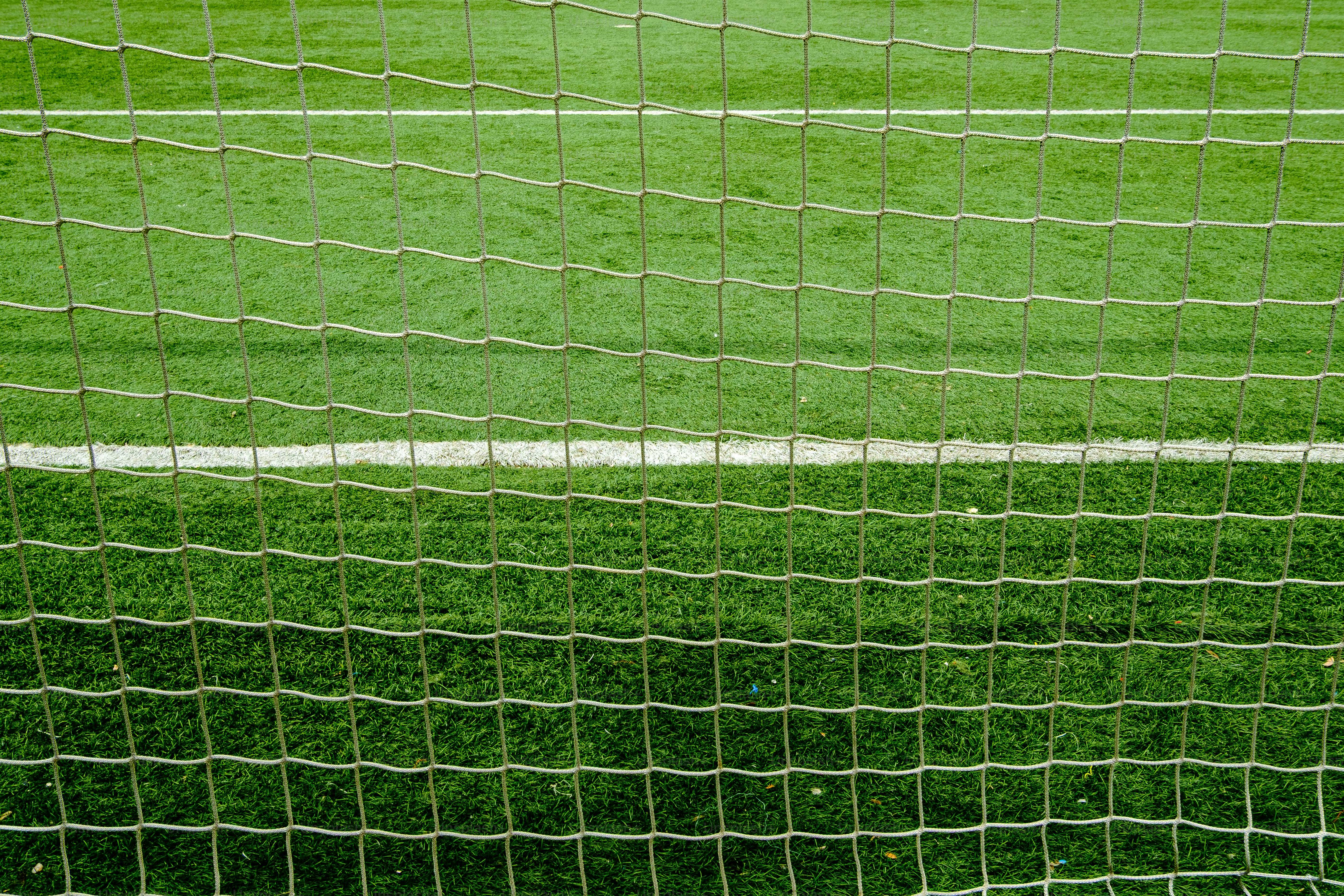 Green soccer field seen through a goal net.