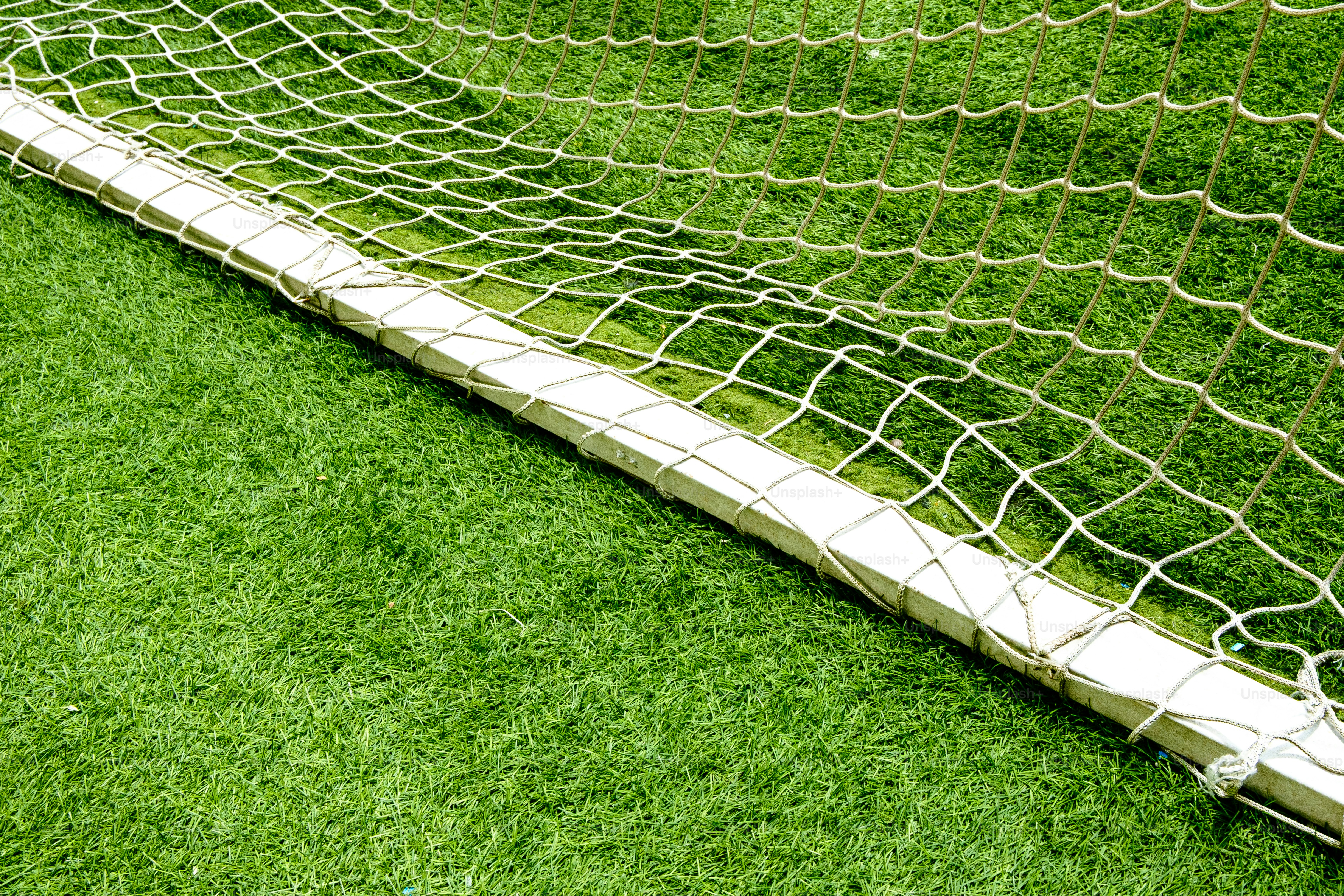 A soccer goal net sits on vibrant green grass.