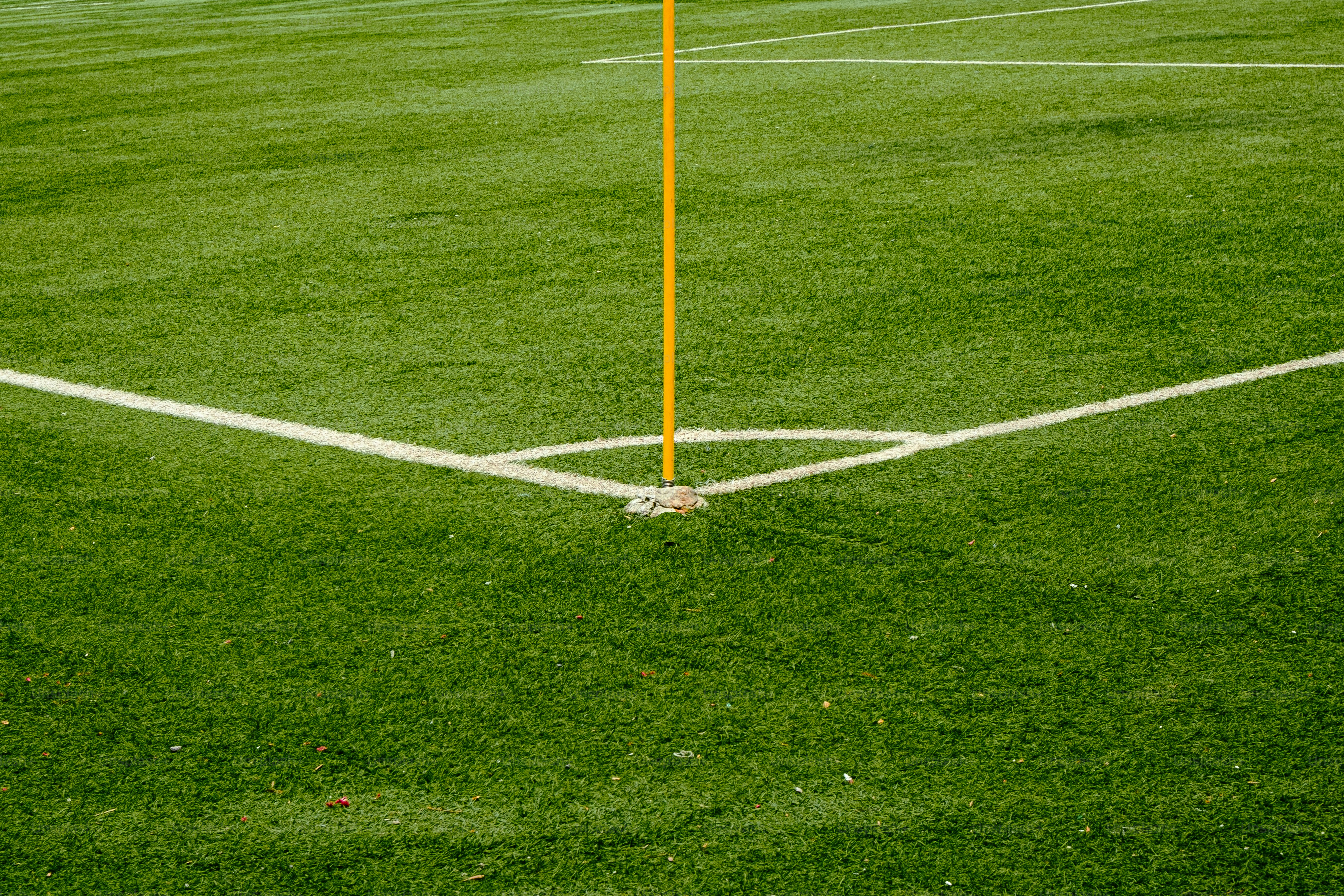 Corner of a green soccer field with a yellow flag.
