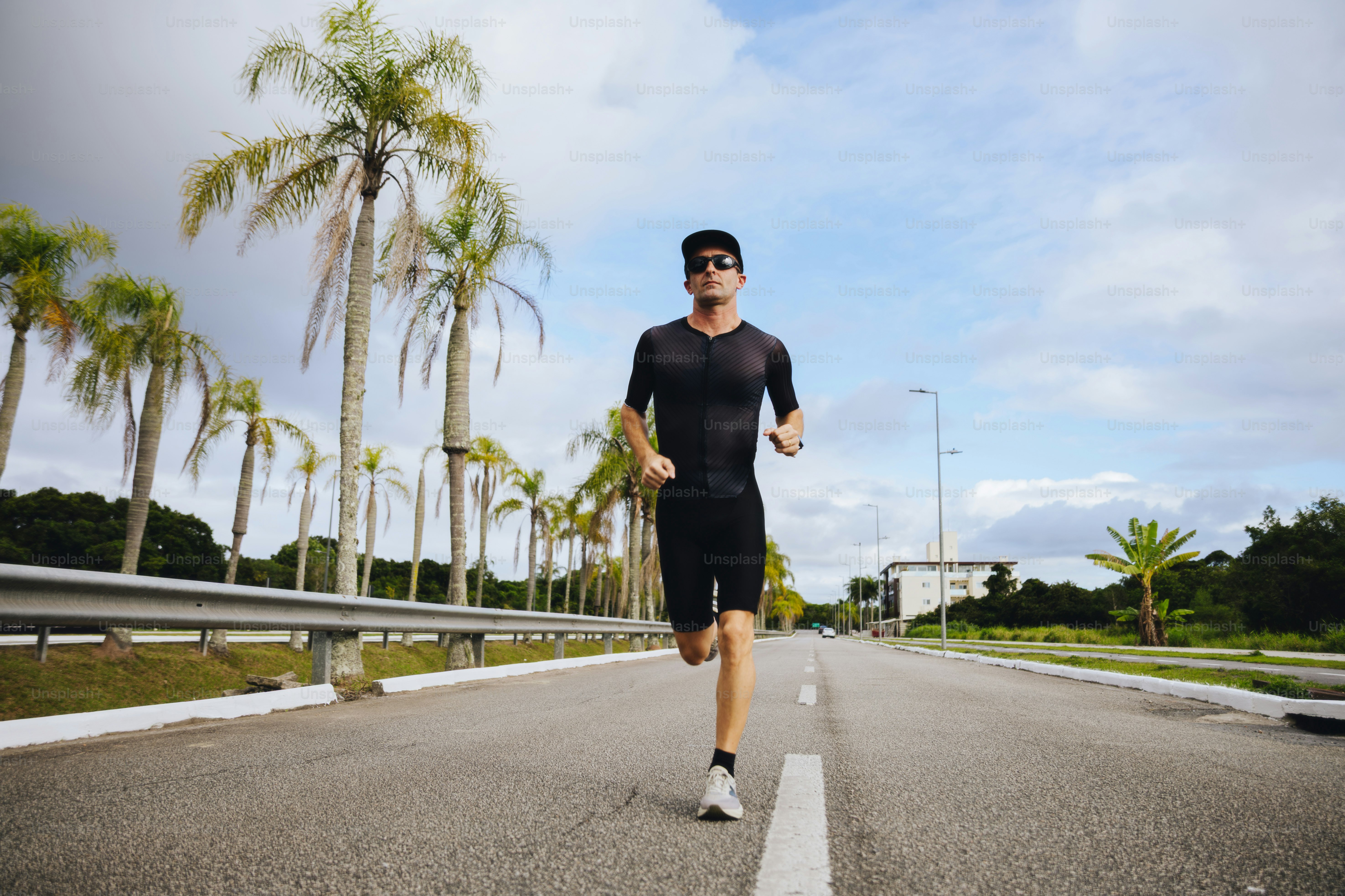 A man running on a road lined with palm trees.