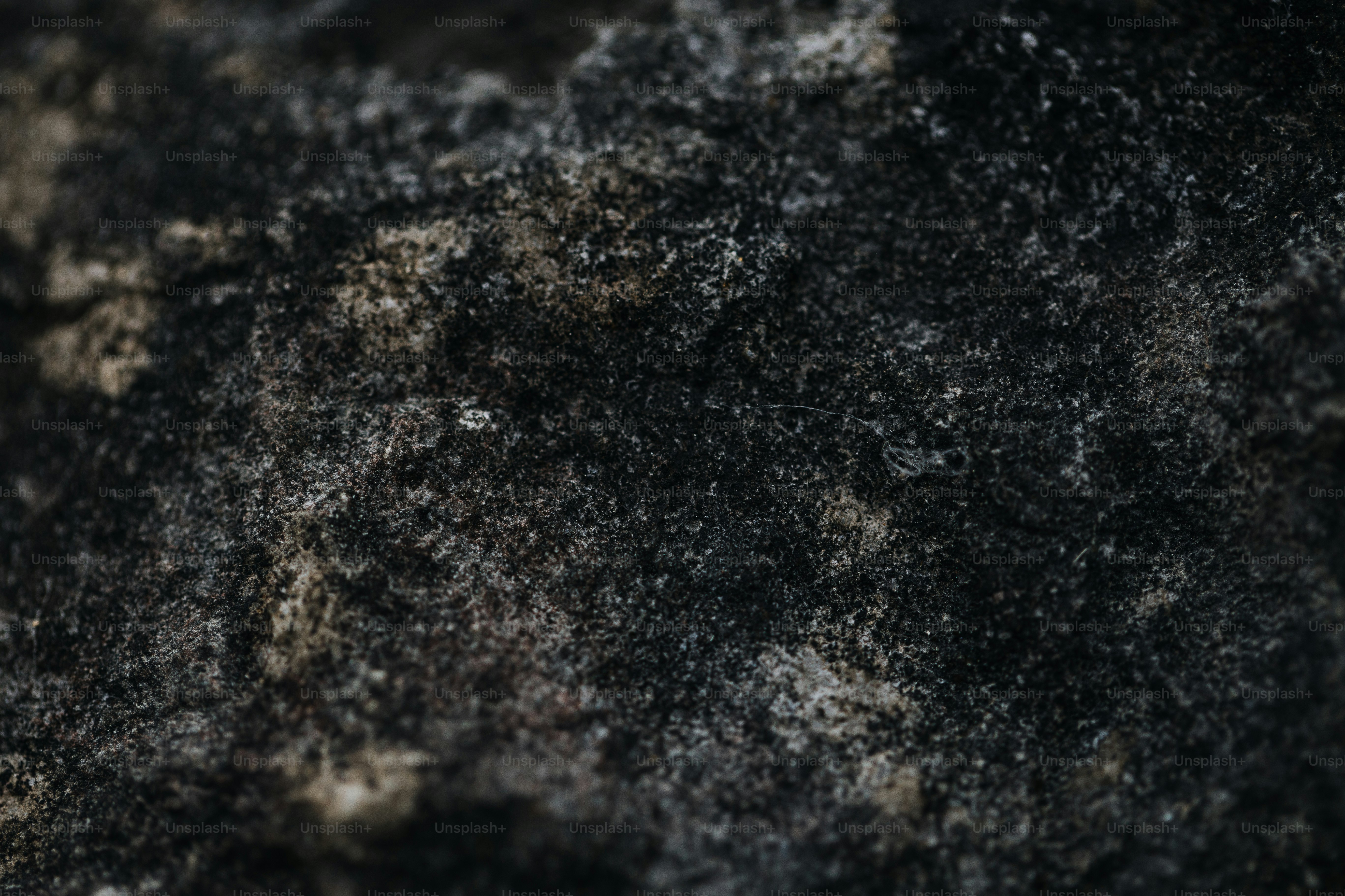 Dark, rough rock texture with subtle light variations.
