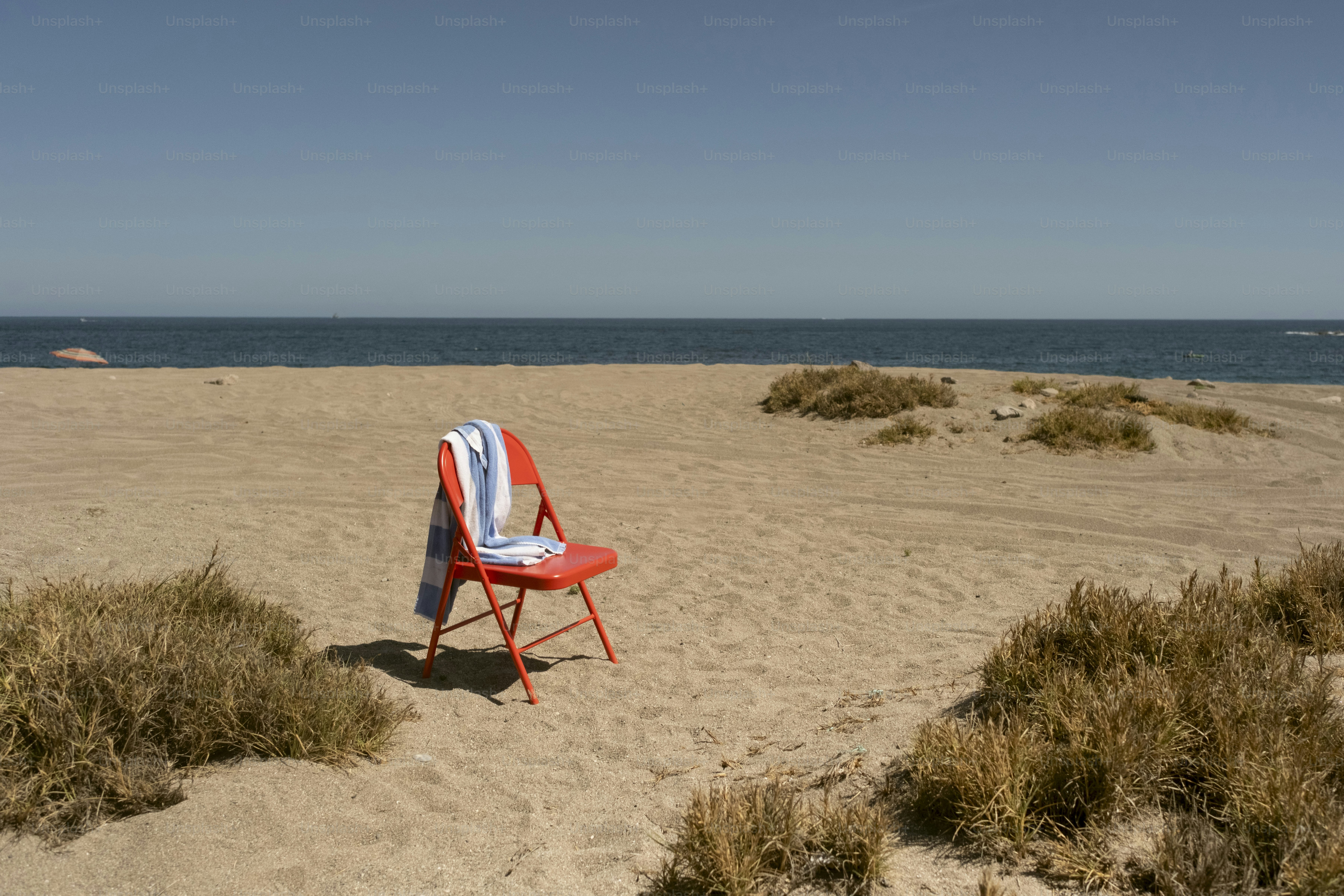 Red chair and towel on sandy beach