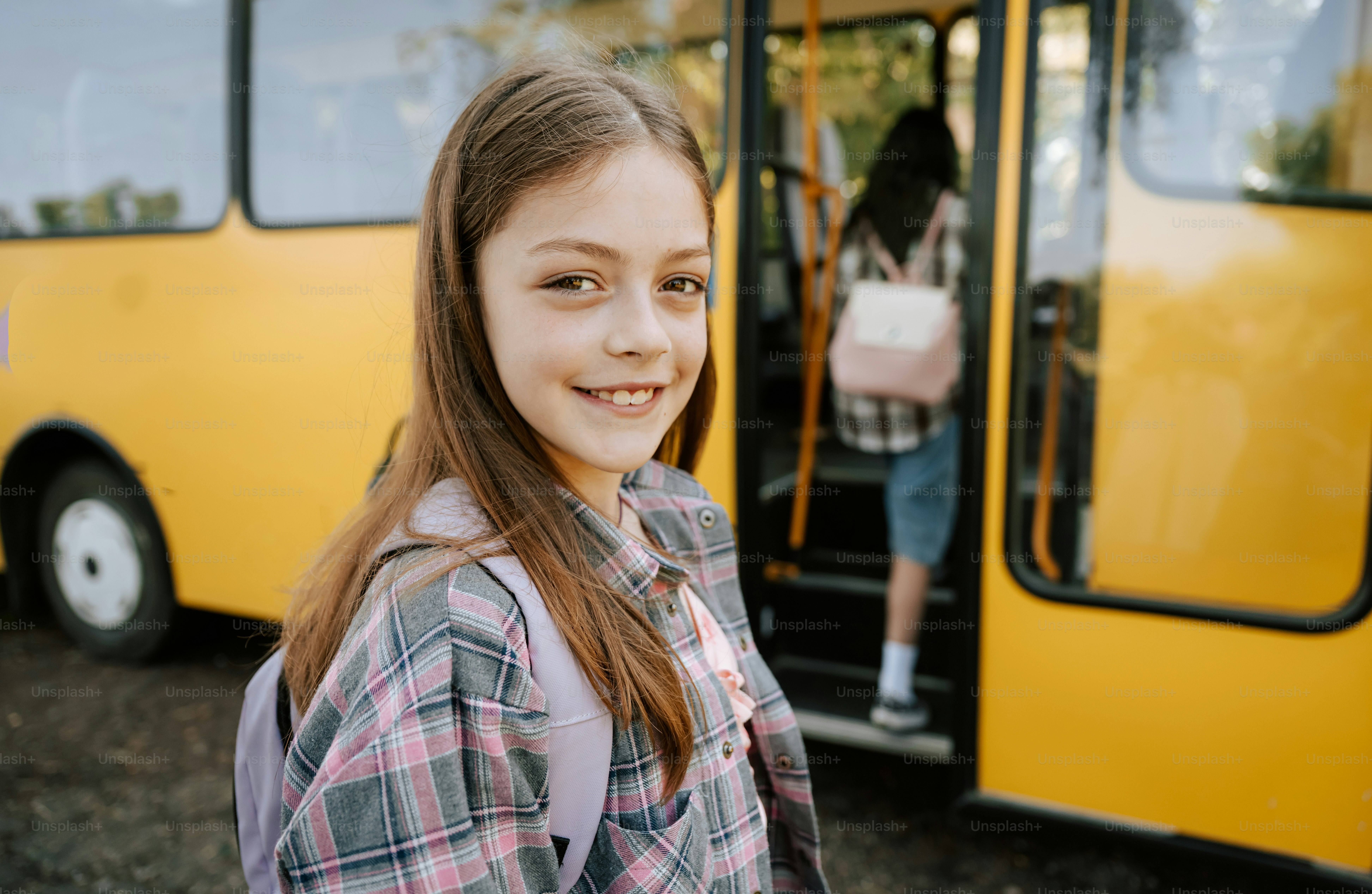 Young girl smiling near a school bus