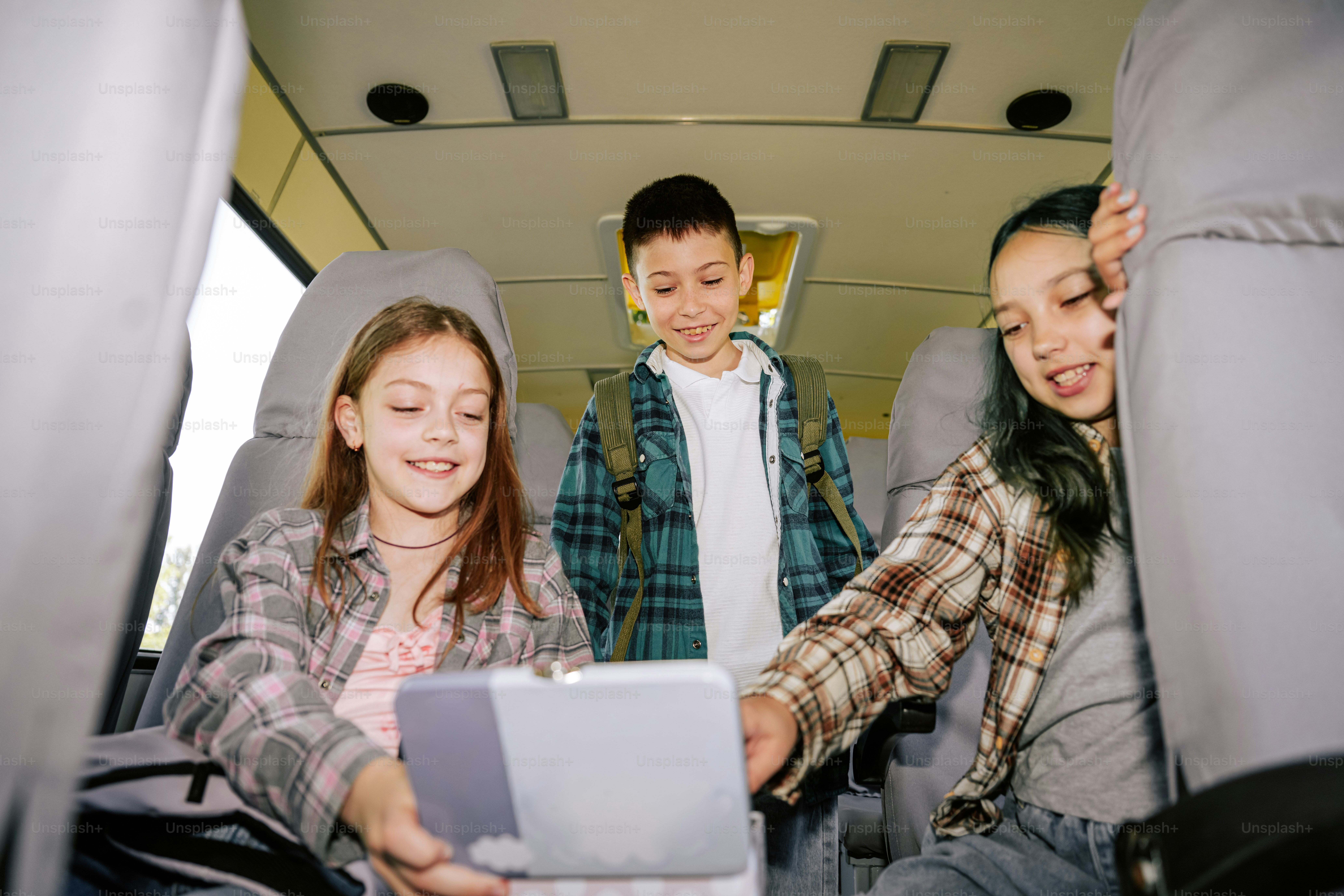 Kids watching a tablet together on a bus