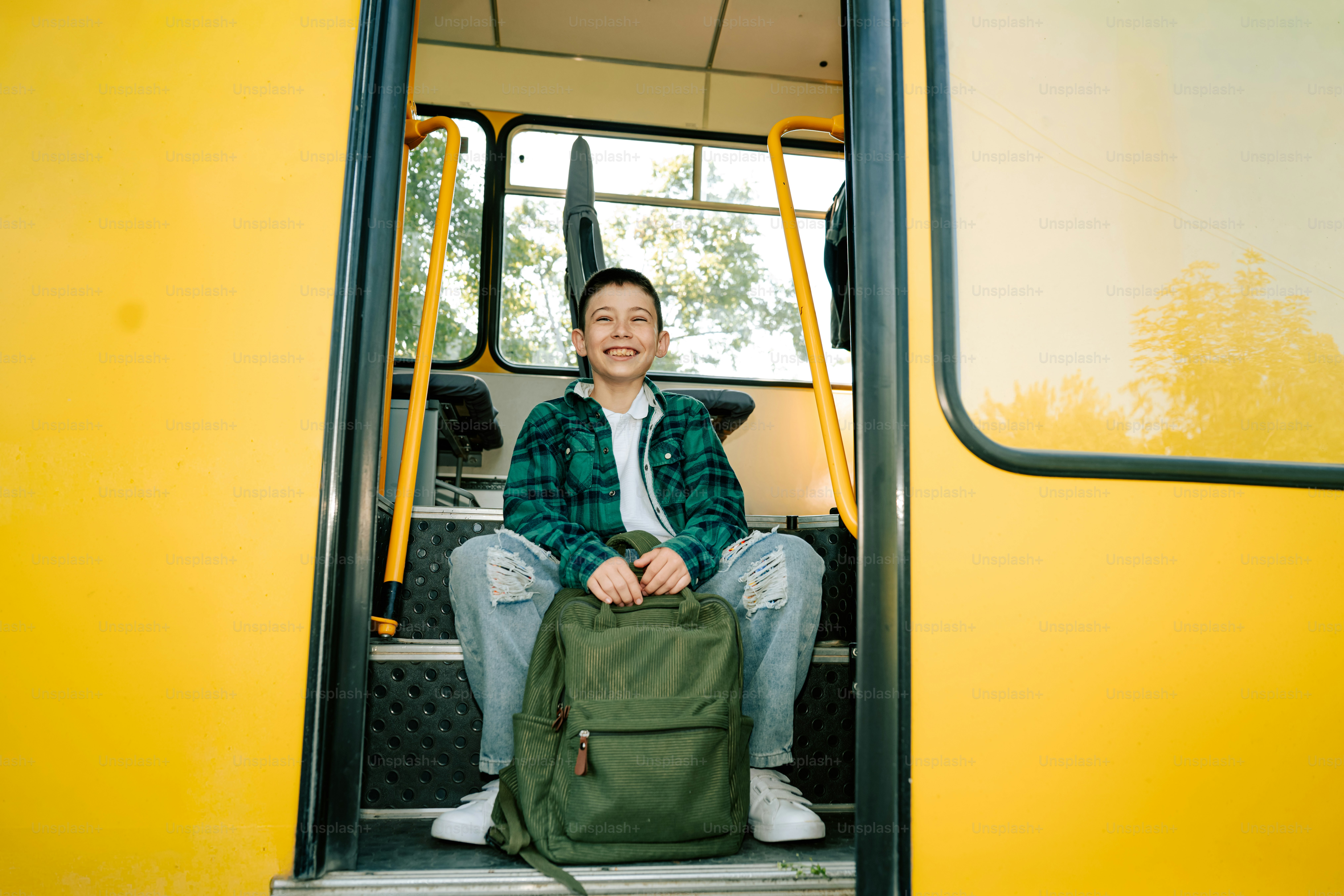 Smiling student sits on bus steps with backpack