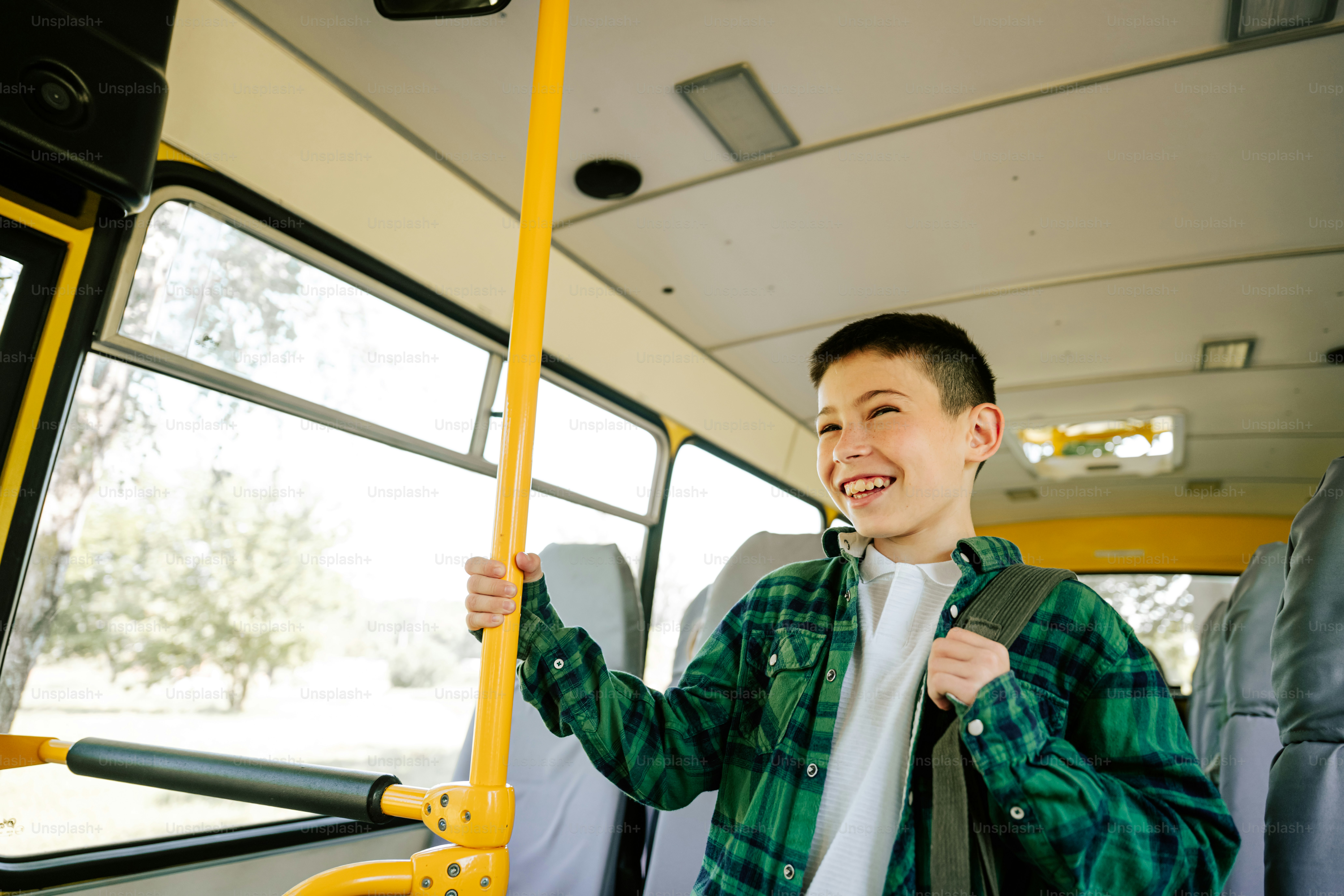 A smiling boy holding a pole inside a bus