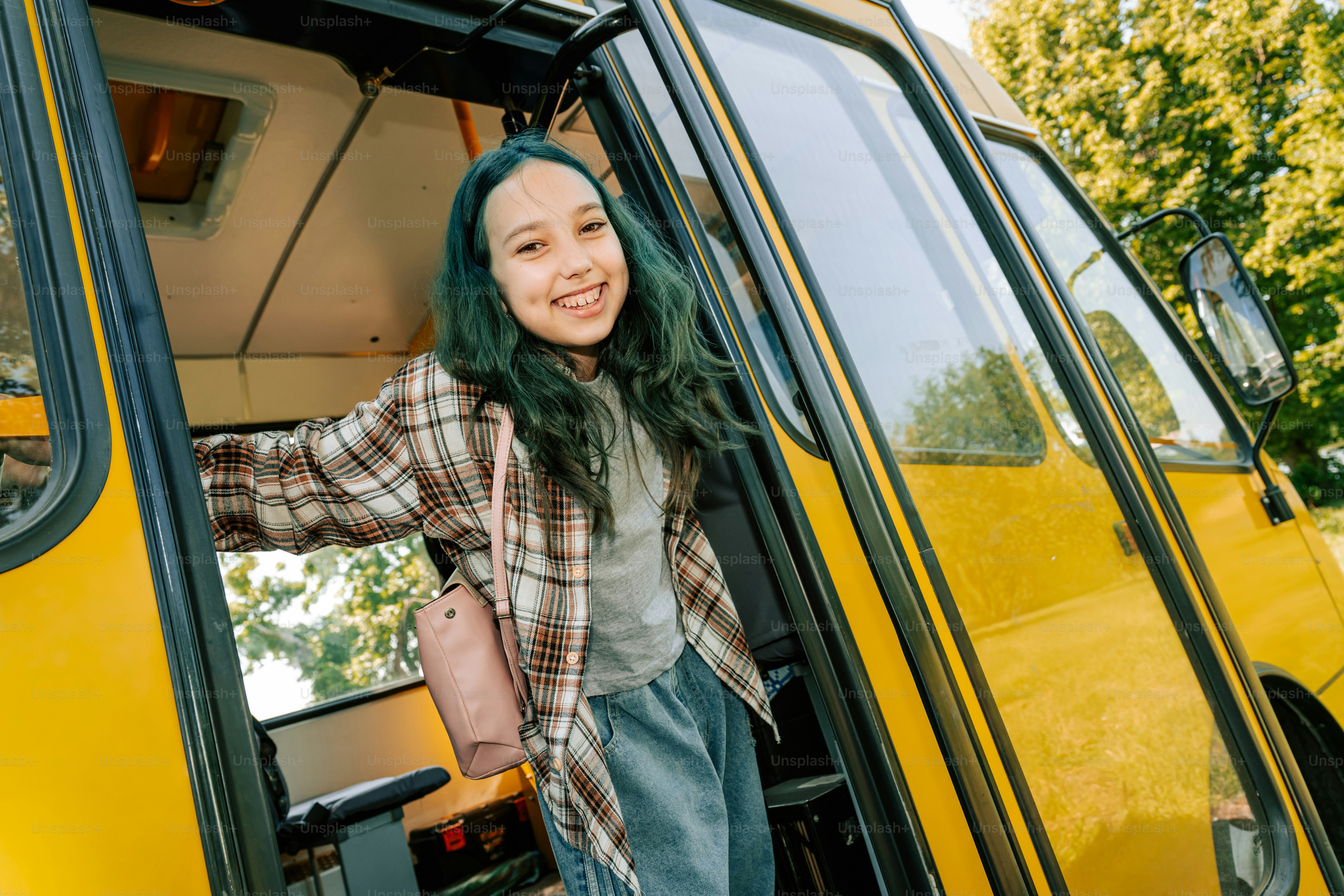 Chica sonriente de pelo verde bajando de un autobús amarillo